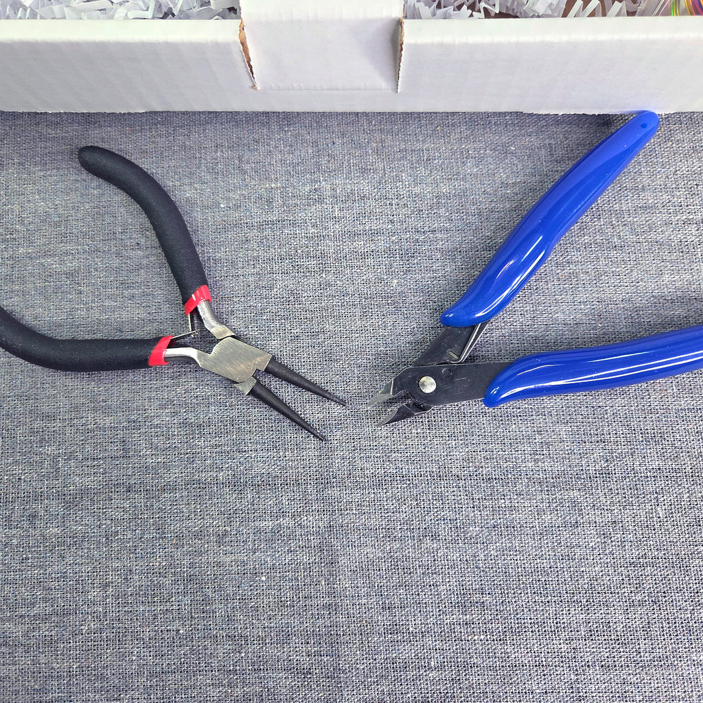 Pair of black and red pliers and a blue and black tool on a gray fabric background
