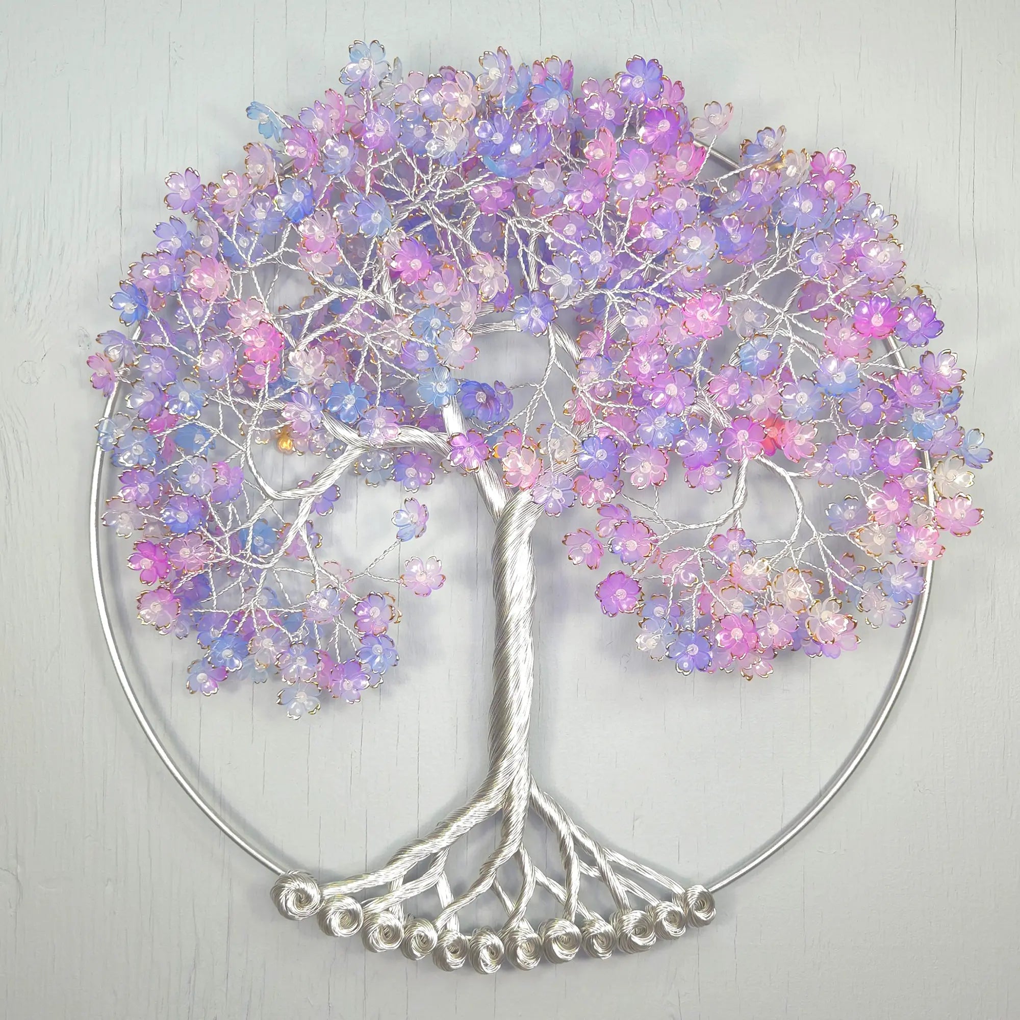 Decorative wall art of a tree with pastel-colored beads on a light gray background