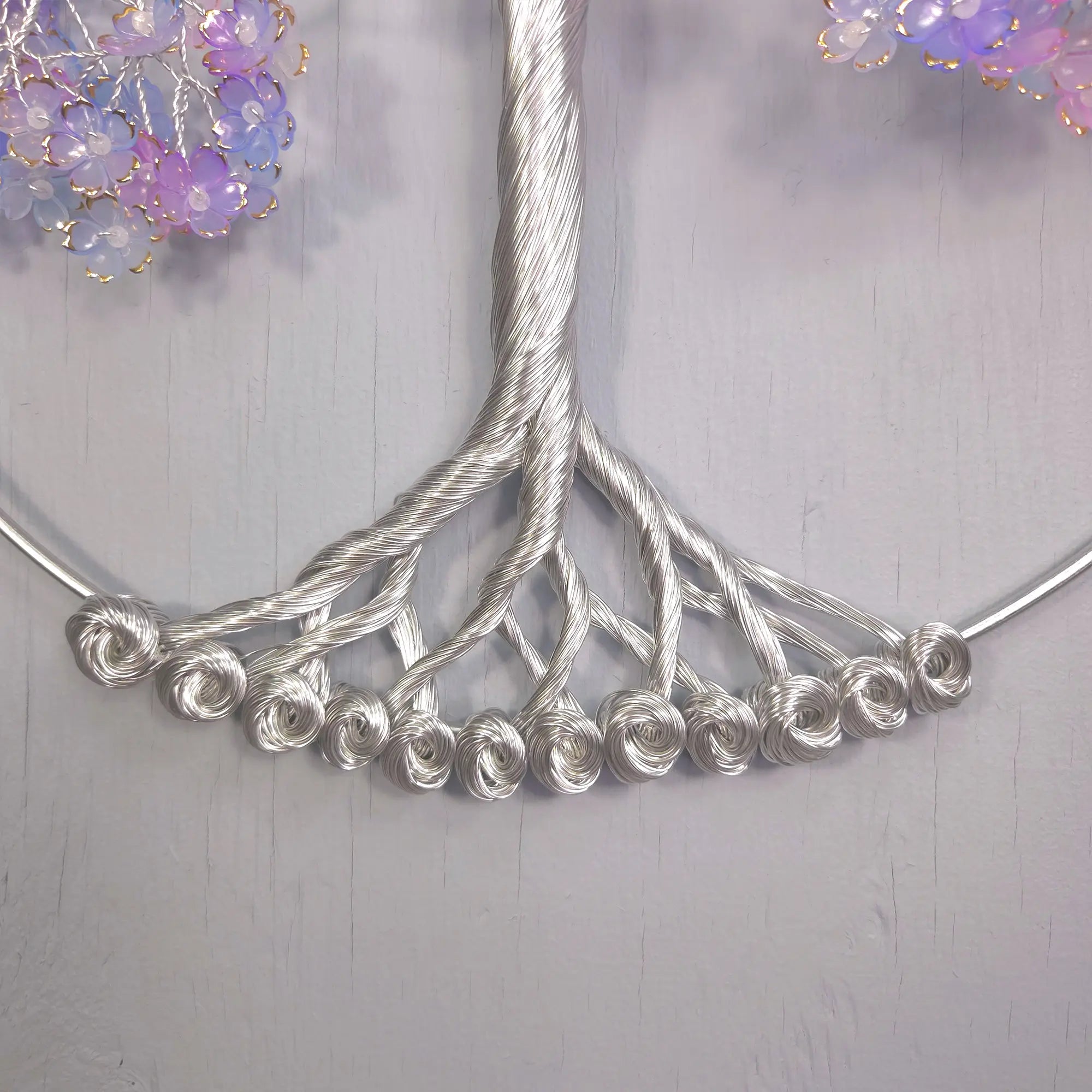 Silver necklace with floral elements on a light gray background