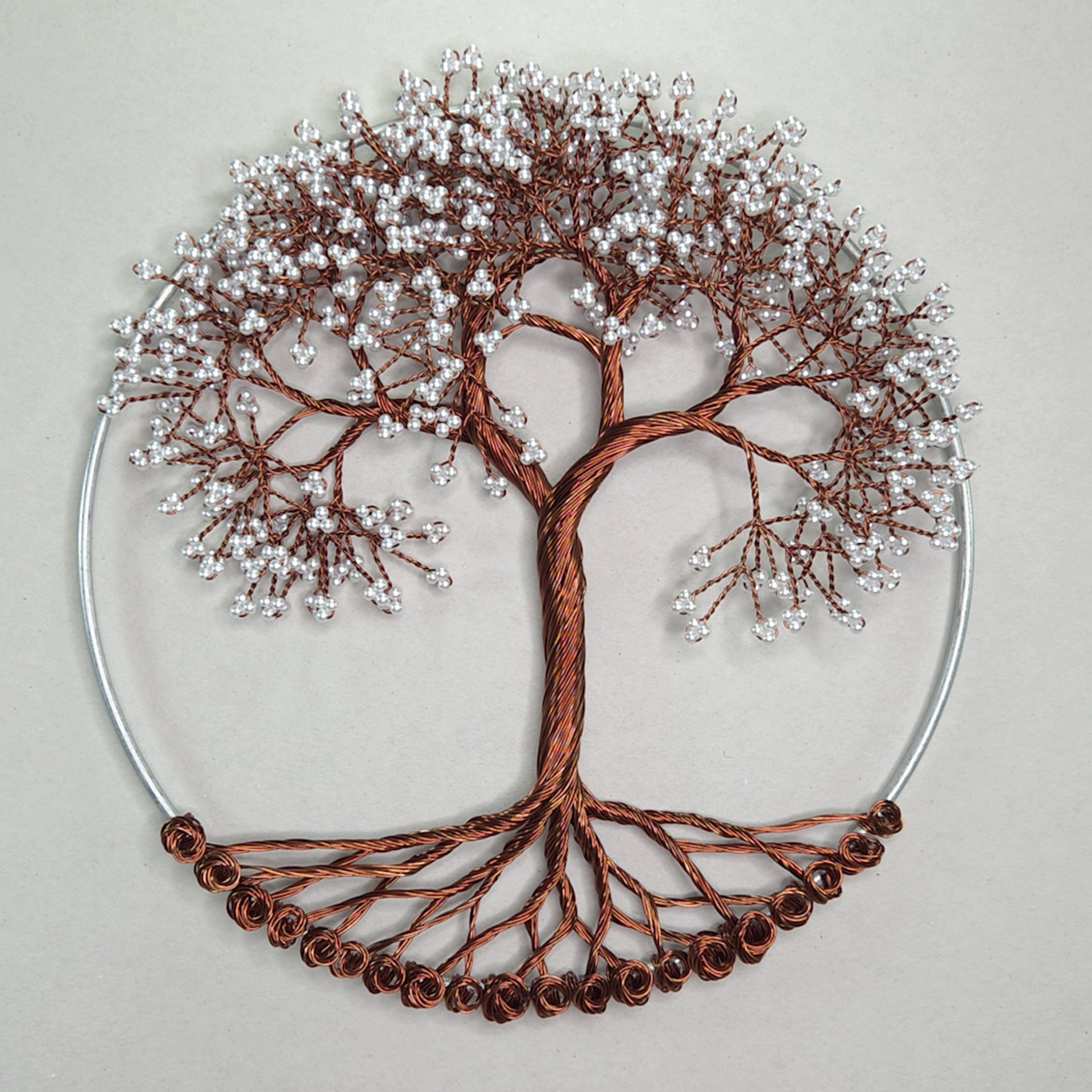 Decorative wall art of a tree with copper branches and silver berries on a beige background
