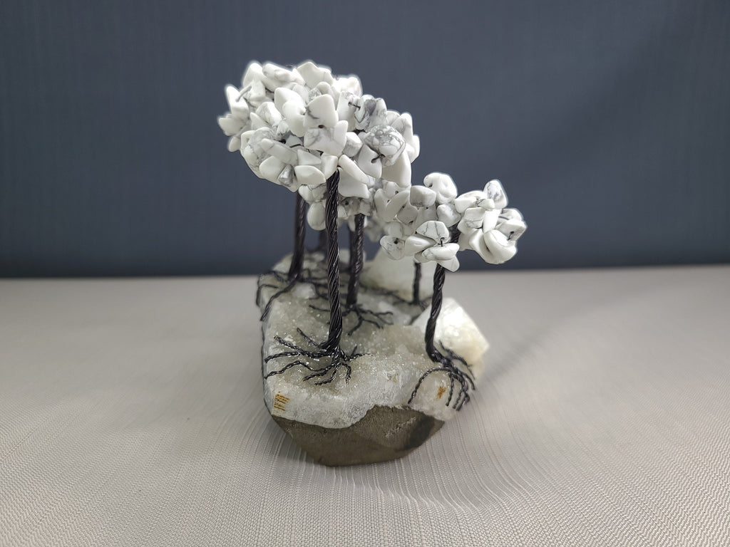 Small sculpture of white trees on a rock base with a plain background