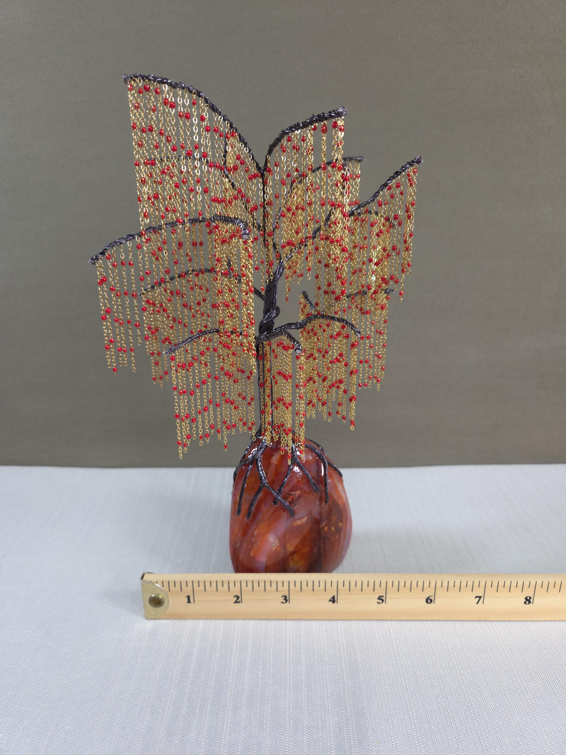Decorative beaded tree sculpture on a gray background with a ruler for scale.