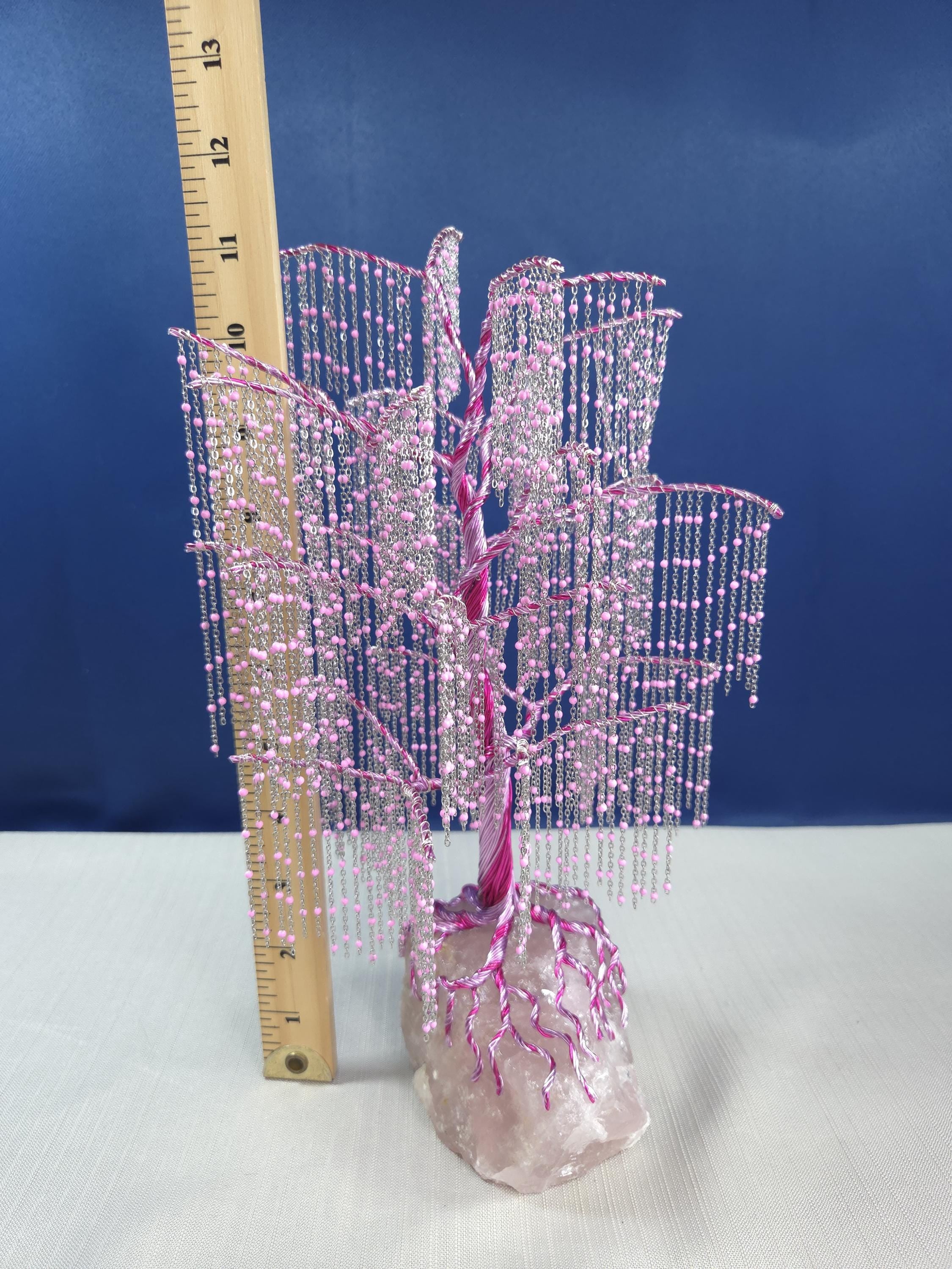 Decorative pink beaded tree with a ruler for scale against a blue background