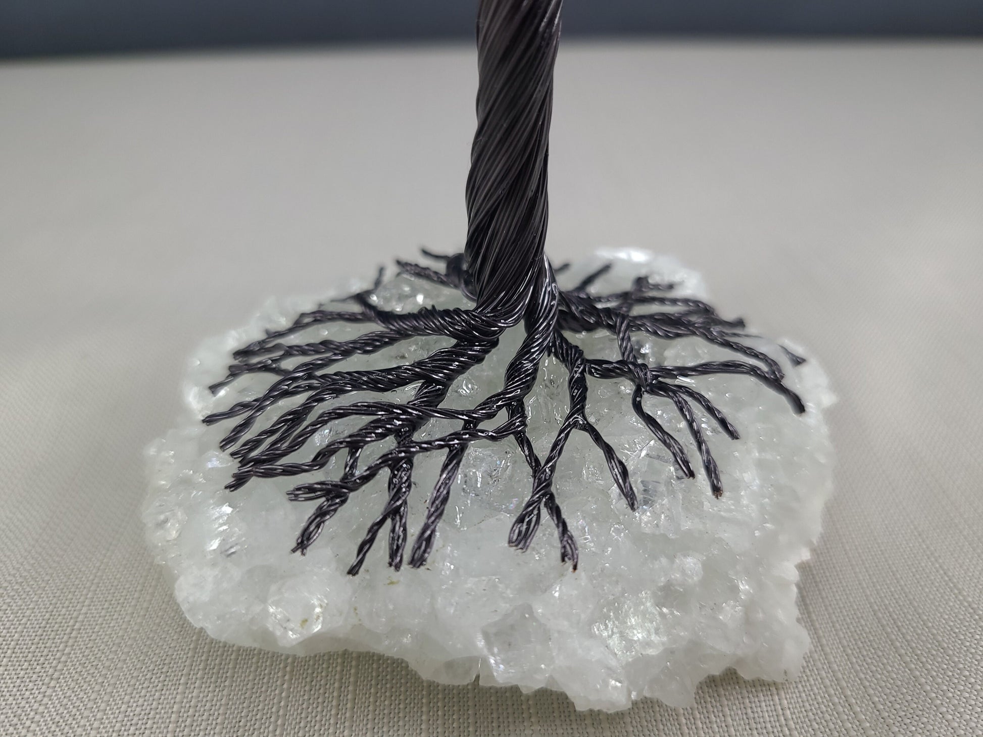 Black cable on a white crystal-like base against a neutral background