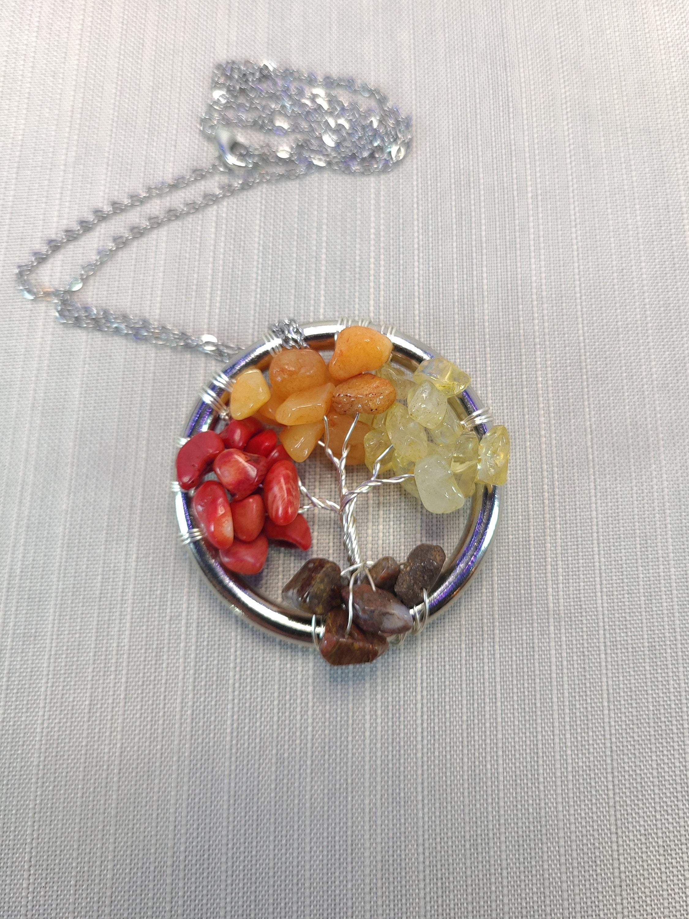 Necklace with a tree-shaped pendant made of multicolored stones on a light fabric background