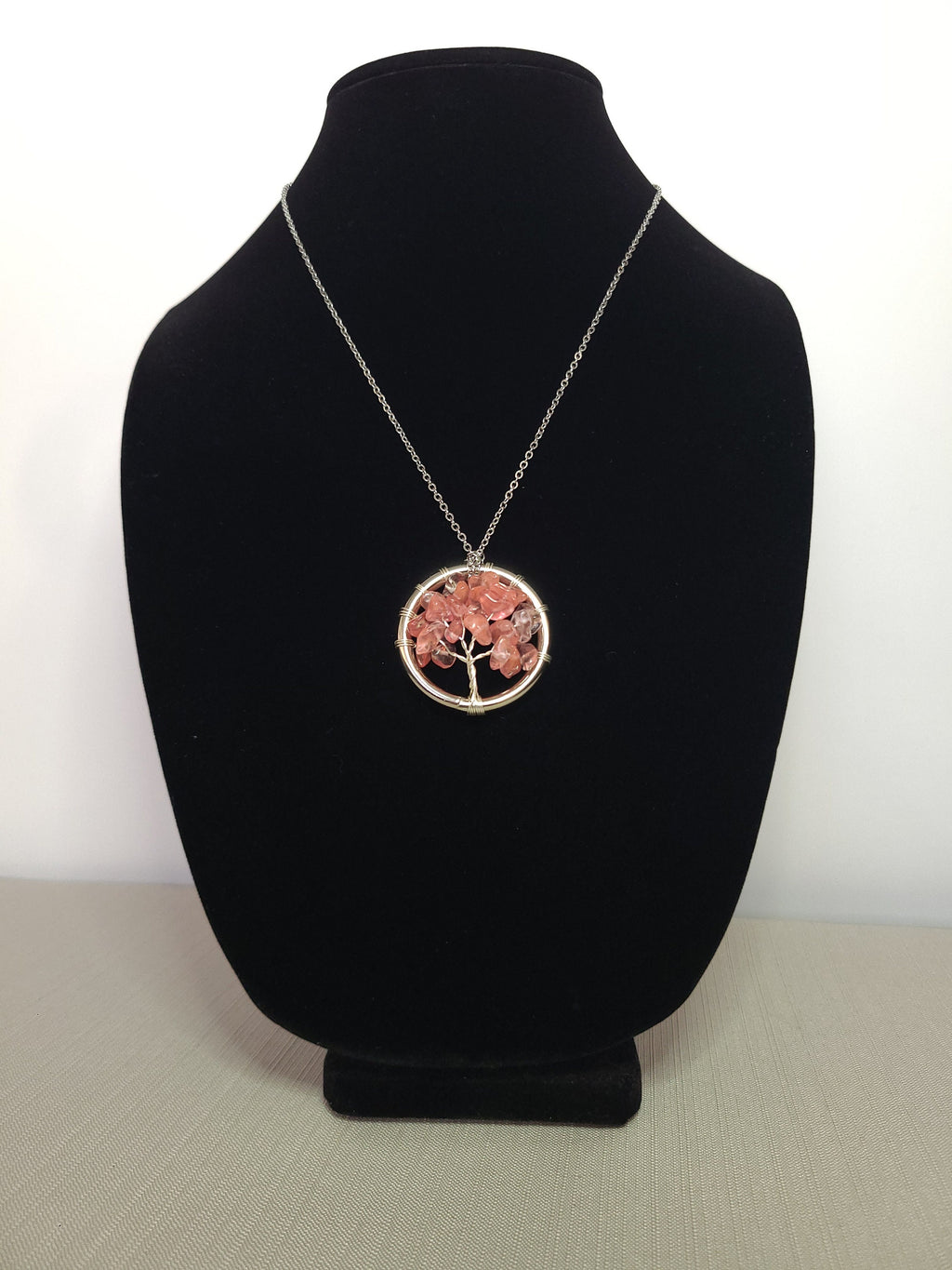 Necklace with a tree of life pendant on a black velvet stand against a white background