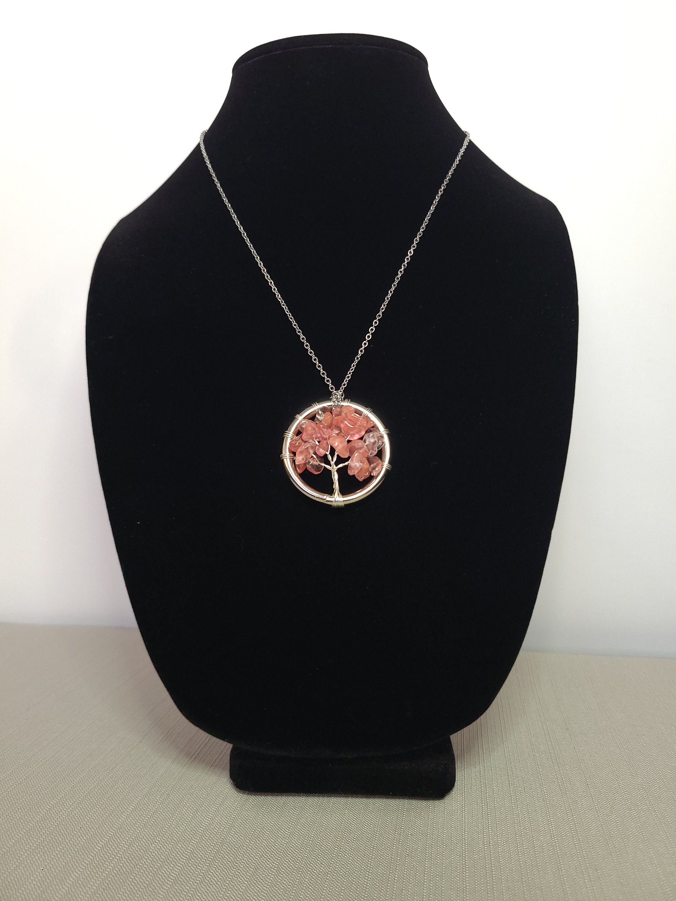 Necklace with a tree of life pendant on a black velvet stand against a white background