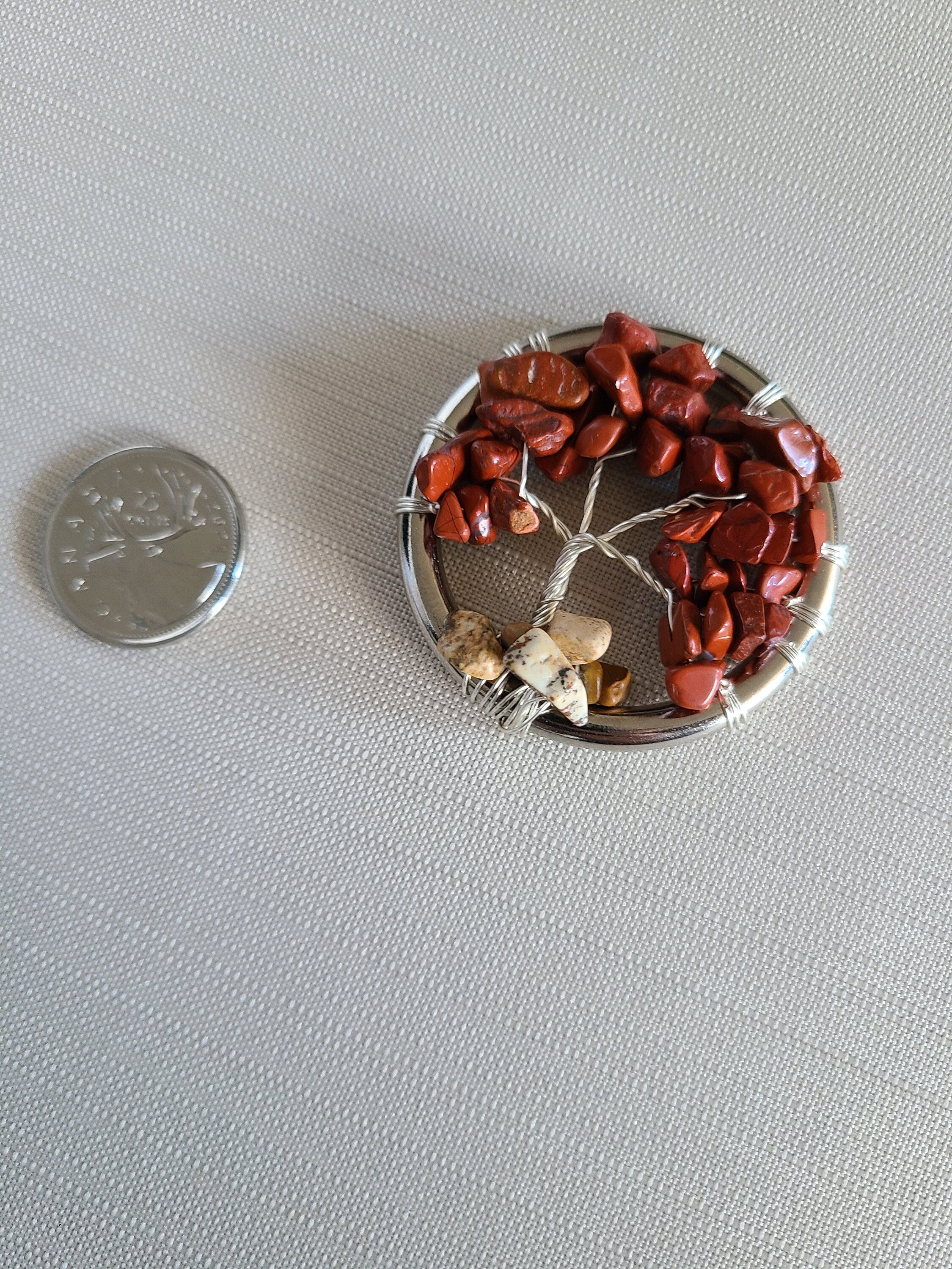 Small circular stone arrangement with a coin for scale on a light gray background