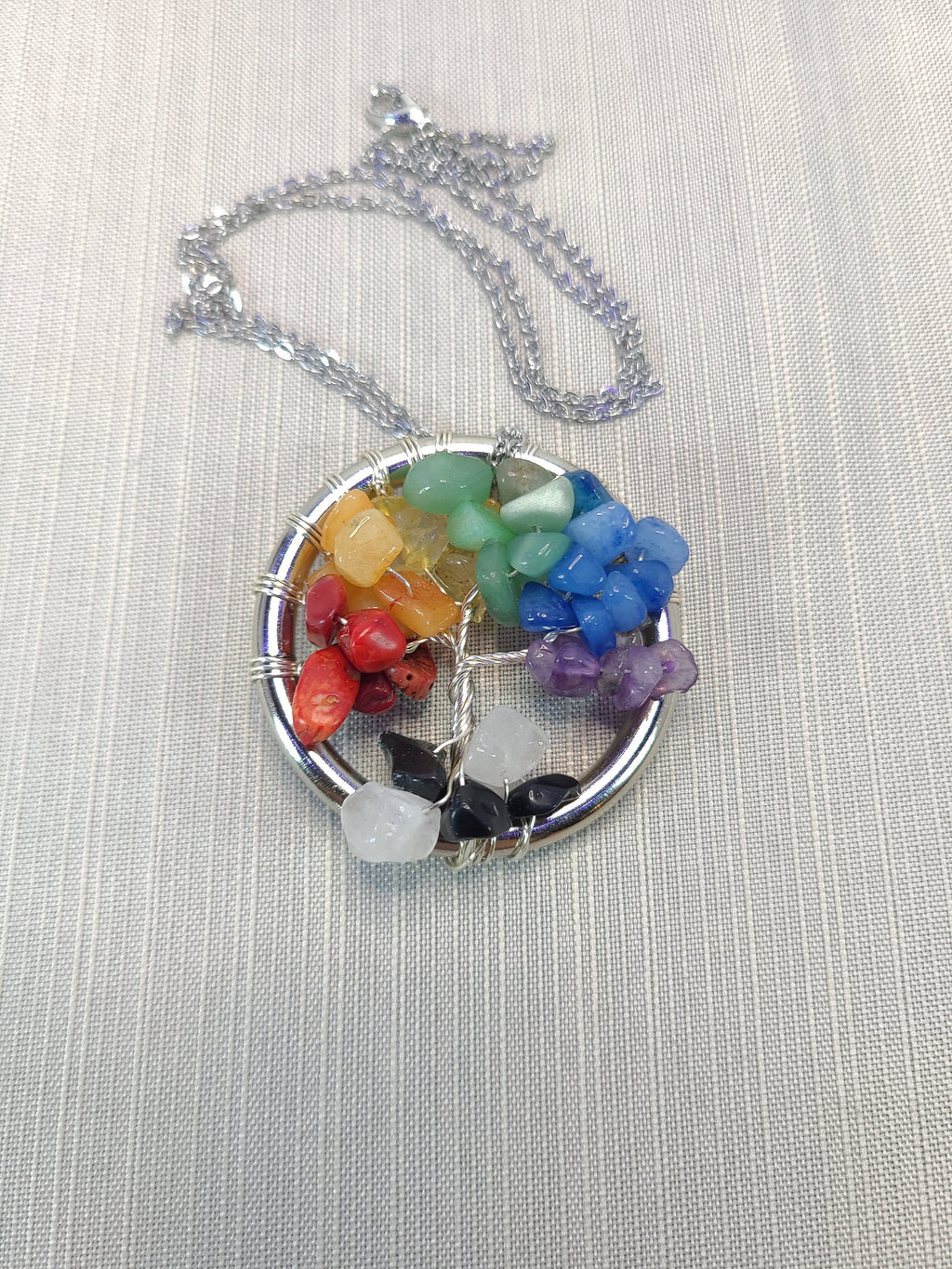 Colorful chakra pendant necklace on a light gray background