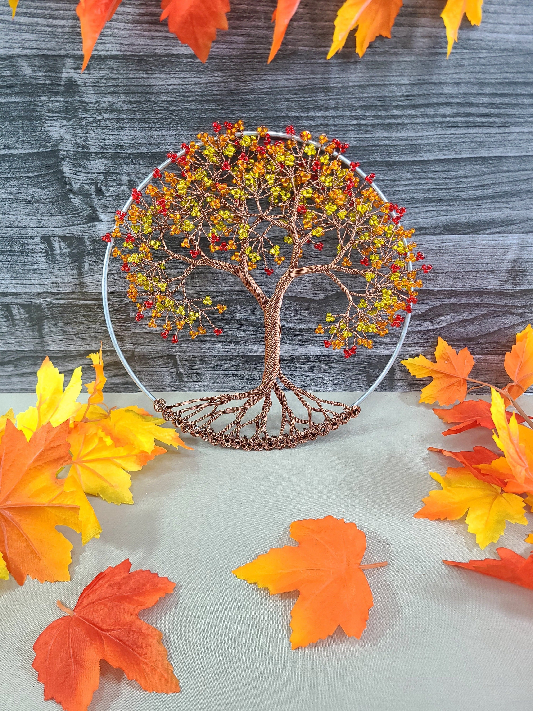 Decorative wire tree with autumn leaves on a wooden surface