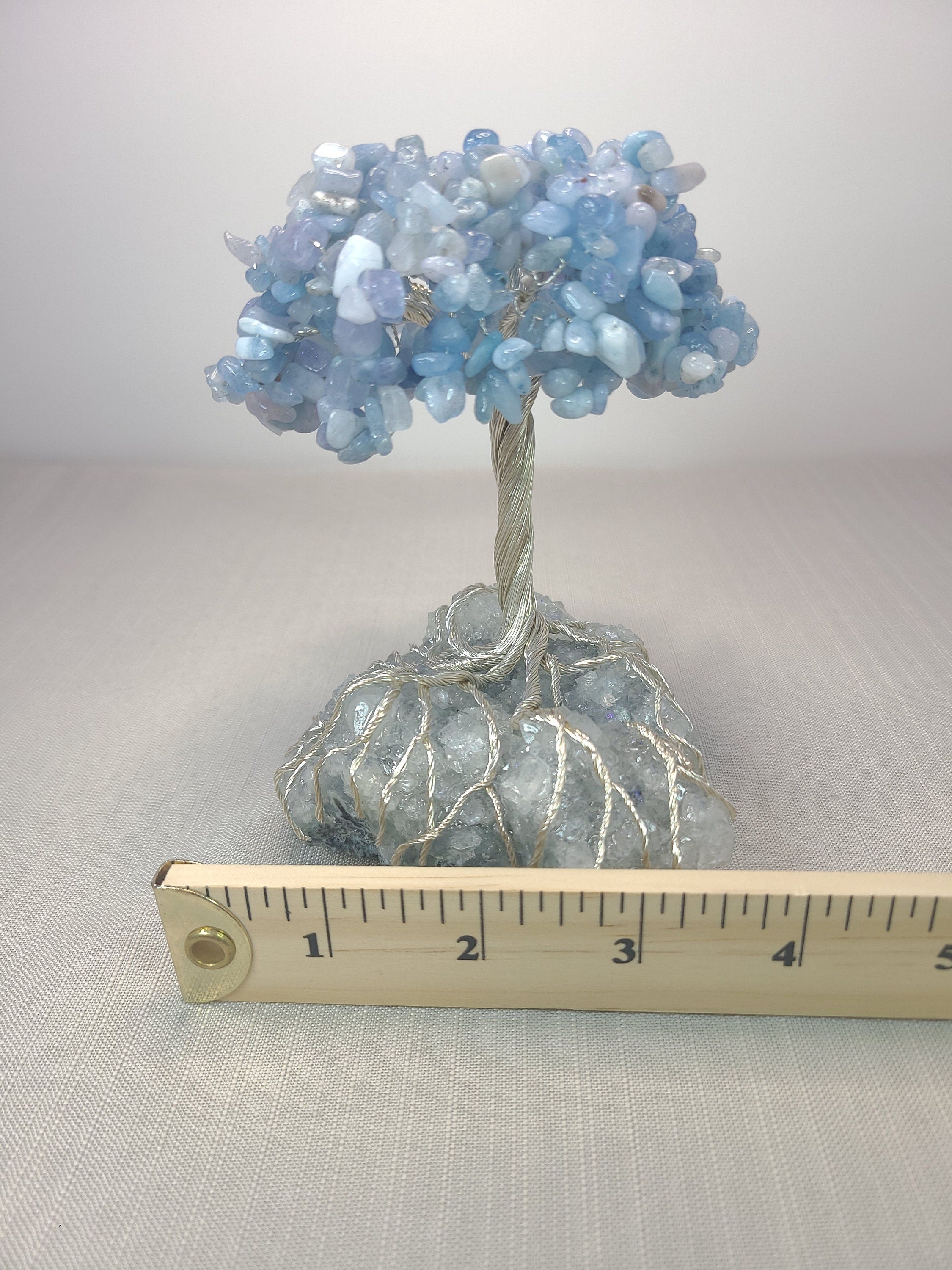 Decorative crystal tree with a ruler for scale on a neutral background
