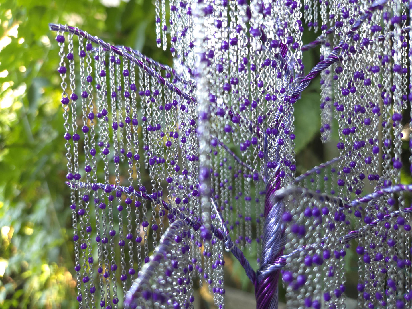 Decorative plant with purple beads against a natural background