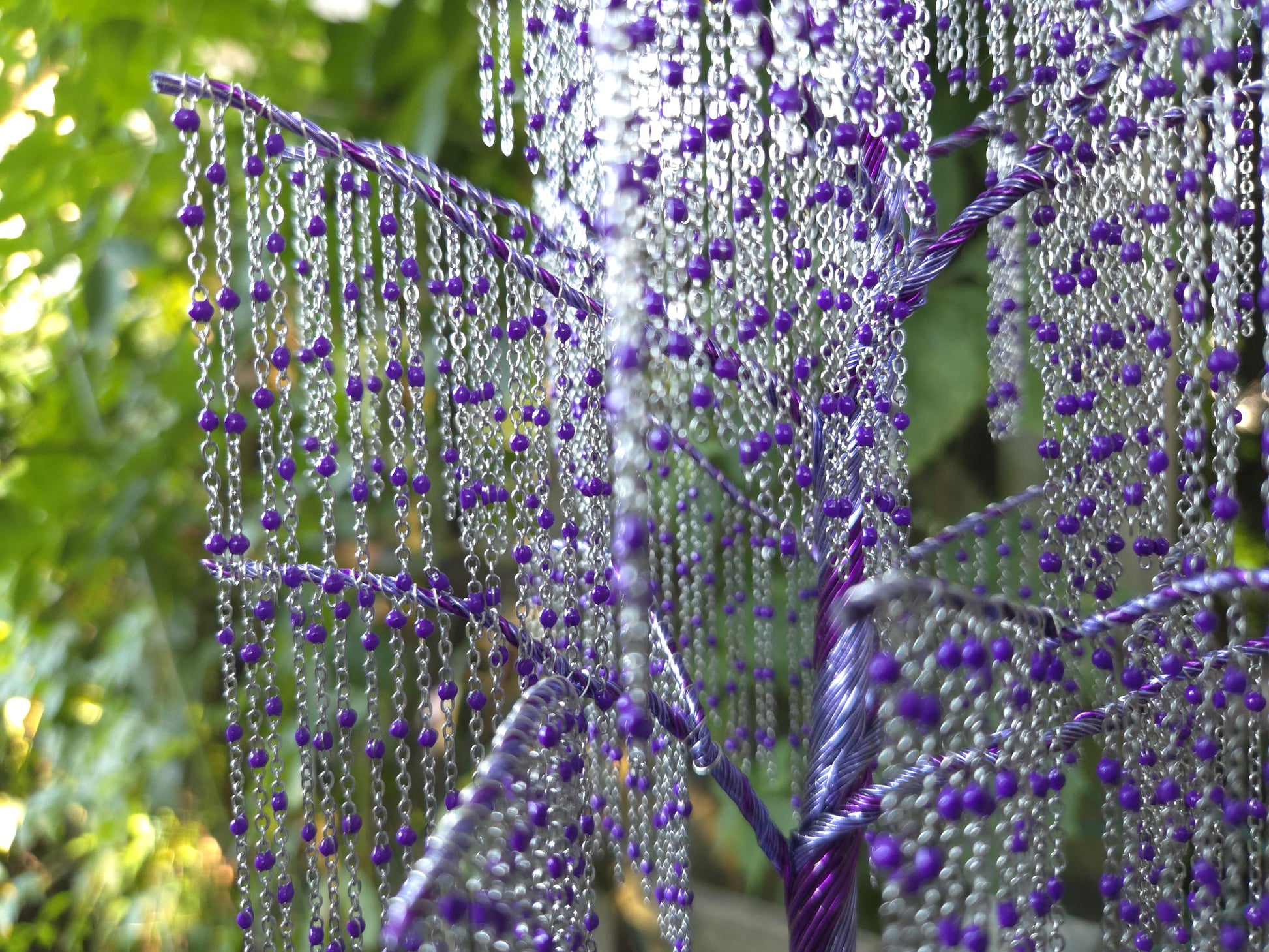 Decorative plant with purple beads against a natural background