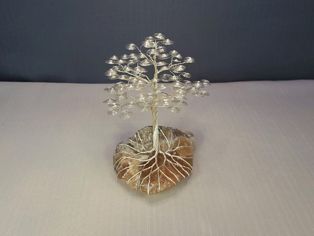 Decorative tree sculpture on a stone base against a dark background