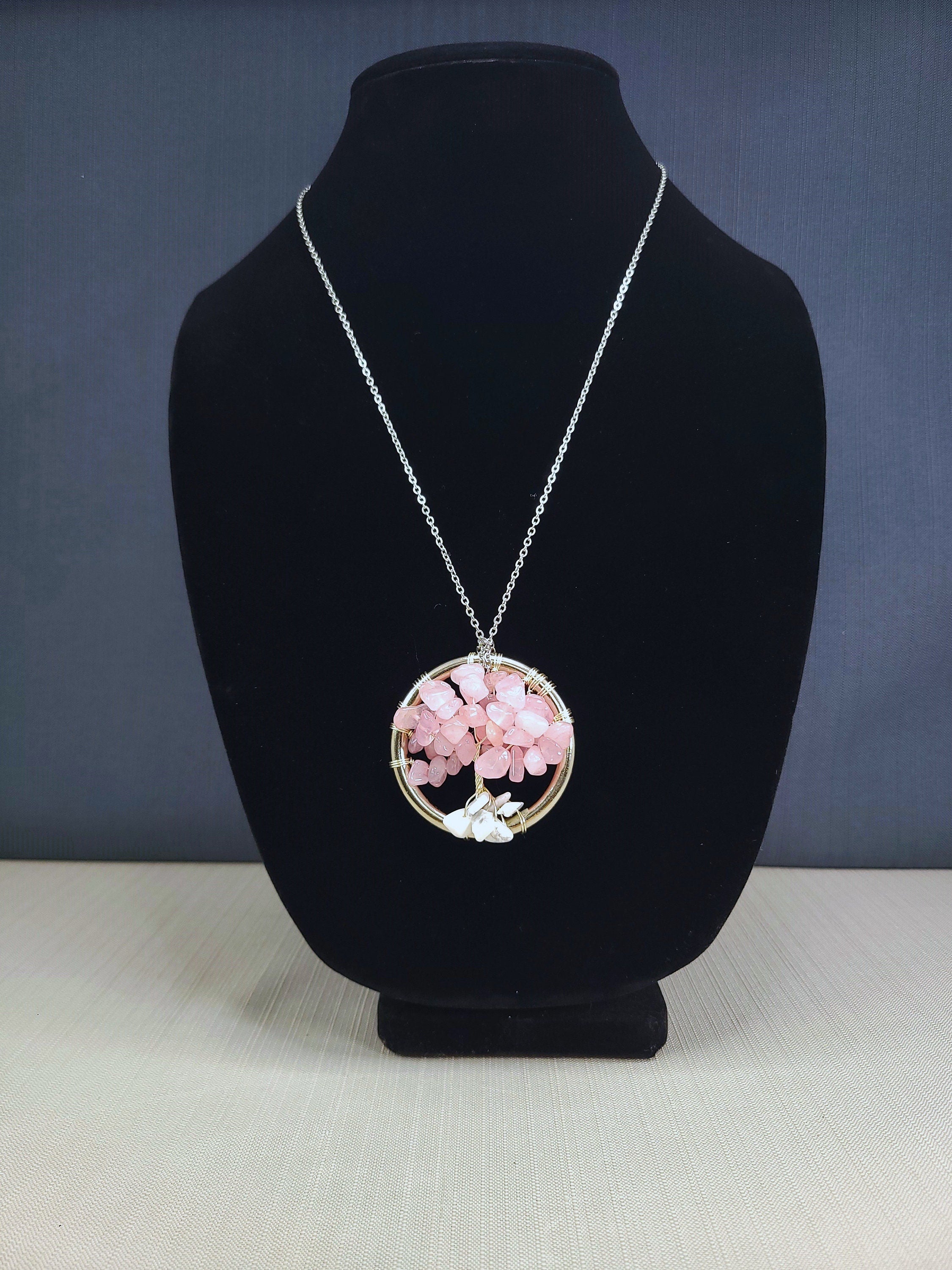Necklace with a pink floral pendant on a black bust against a blue background