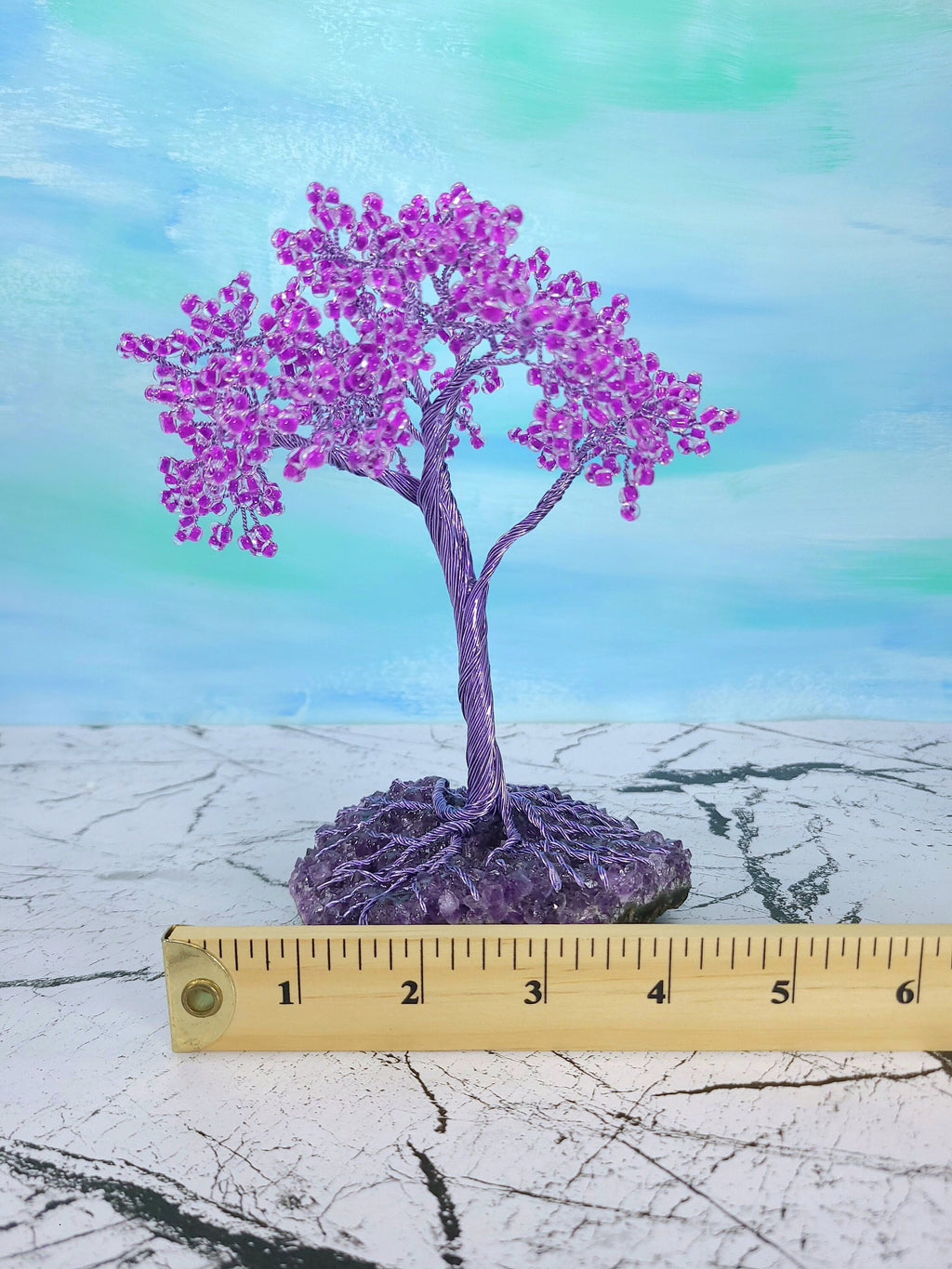 Decorative purple tree with pink flowers on a textured surface with a ruler for scale.