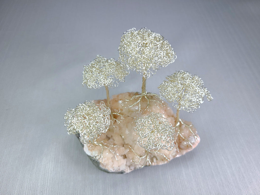 Decorative wire tree sculpture on a stone base against a gray background