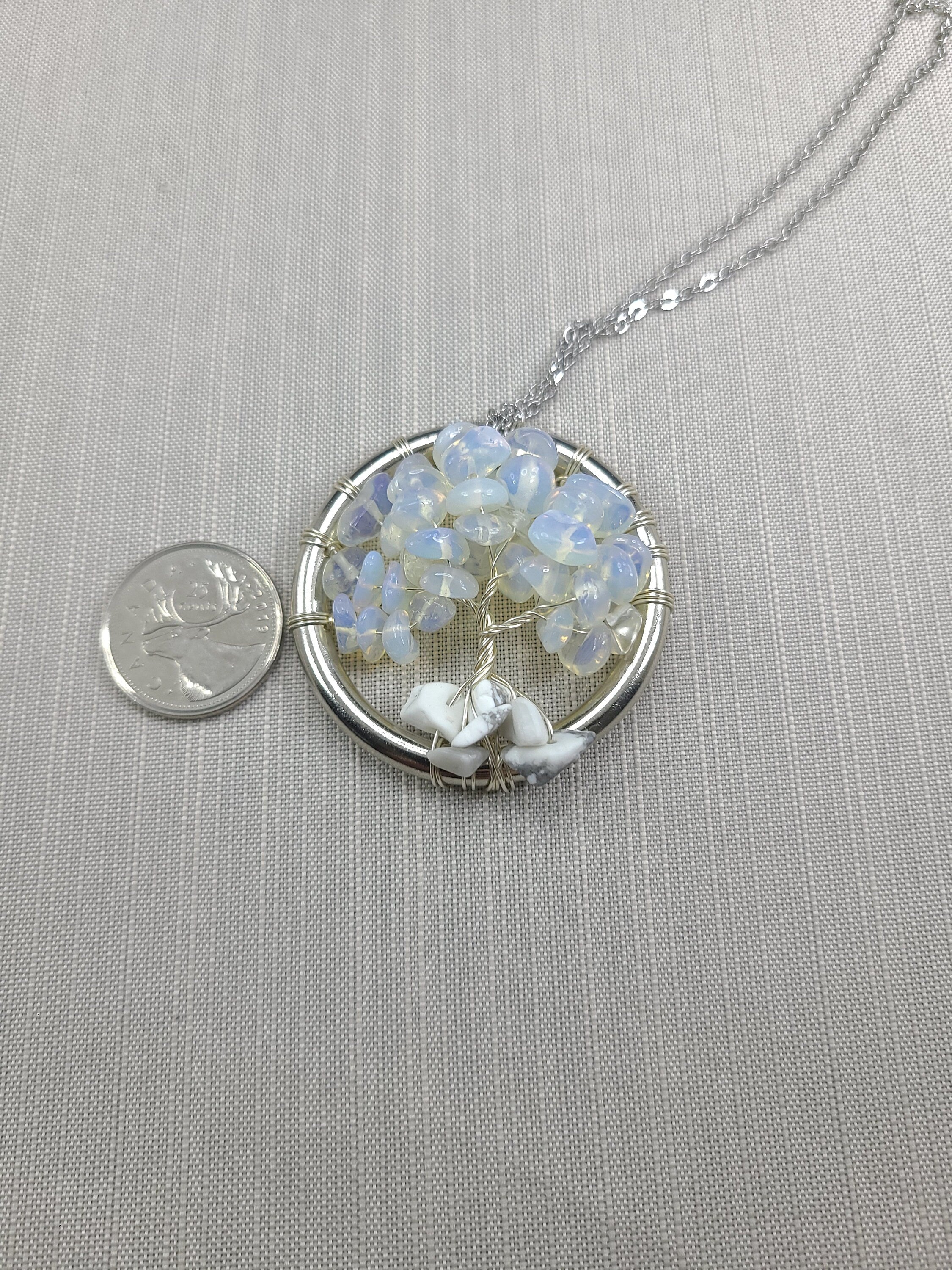 Silver necklace with a circular pendant featuring dried flowers on a gray background