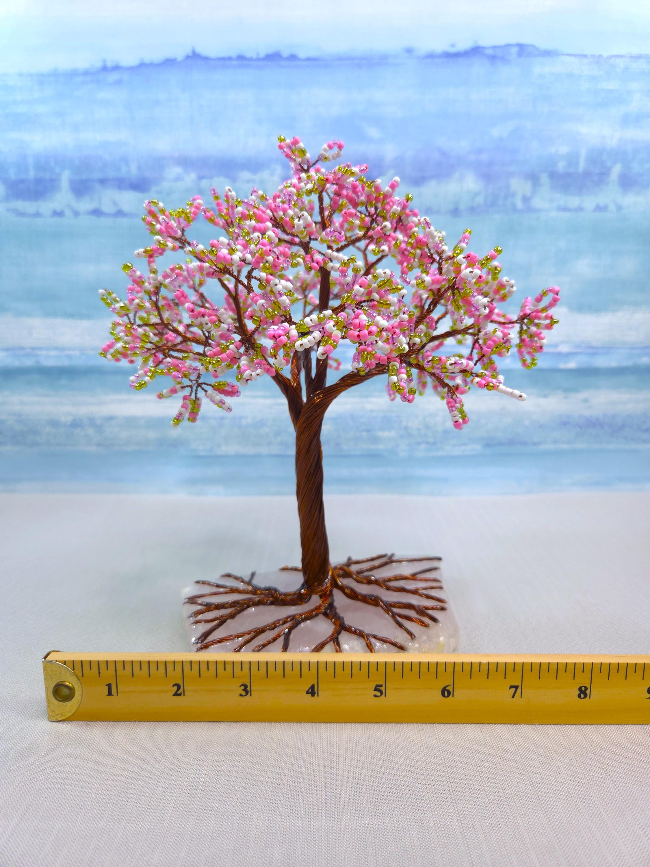 Model of a cherry blossom tree with pink flowers on a white surface, measured against a ruler.