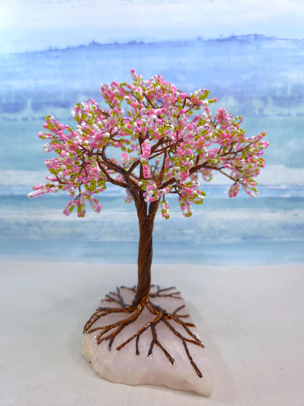 Decorative tree with pink blossoms on a rock against a blurred natural background