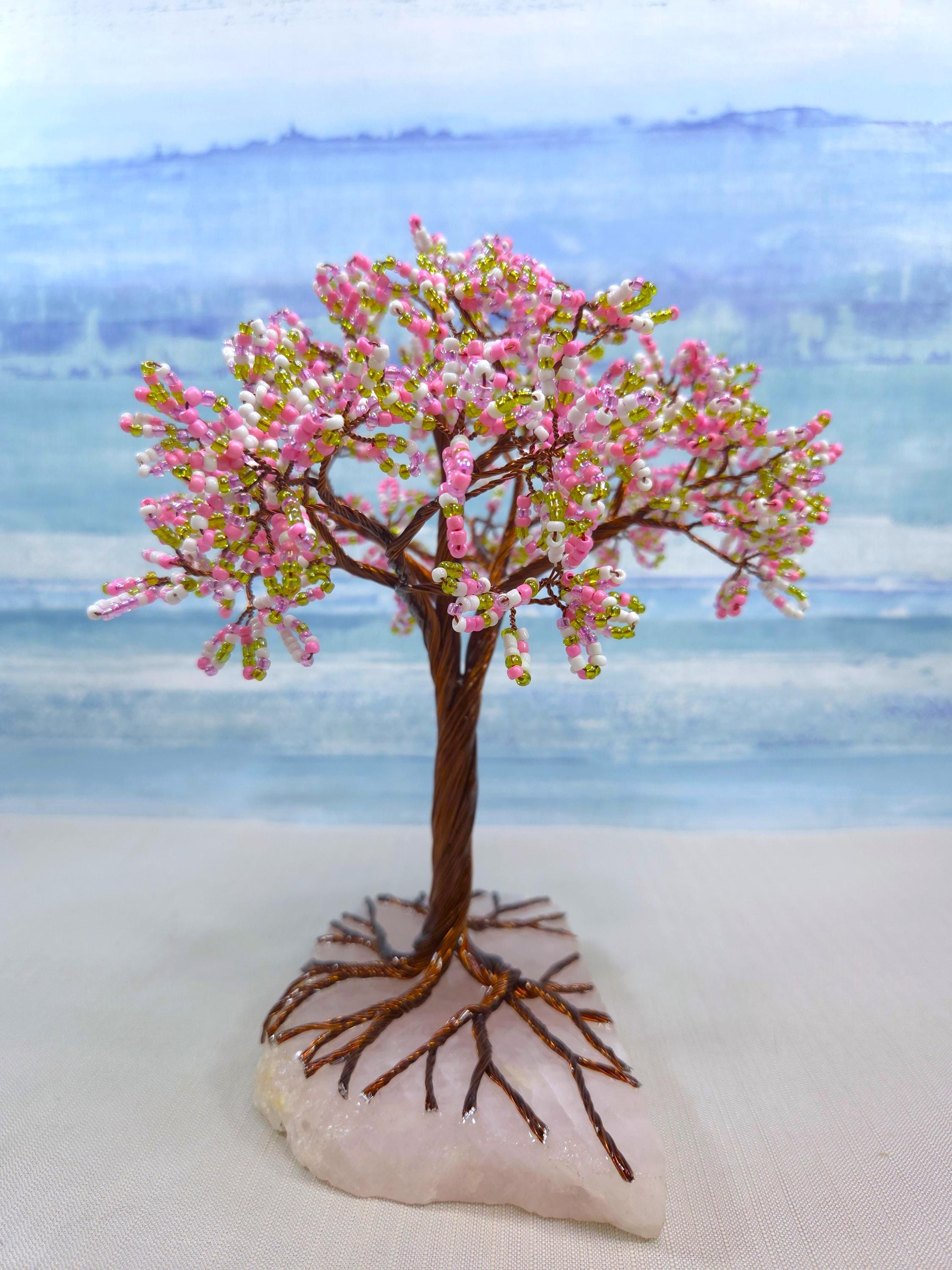 Decorative tree with pink blossoms on a rock against a blurred natural background