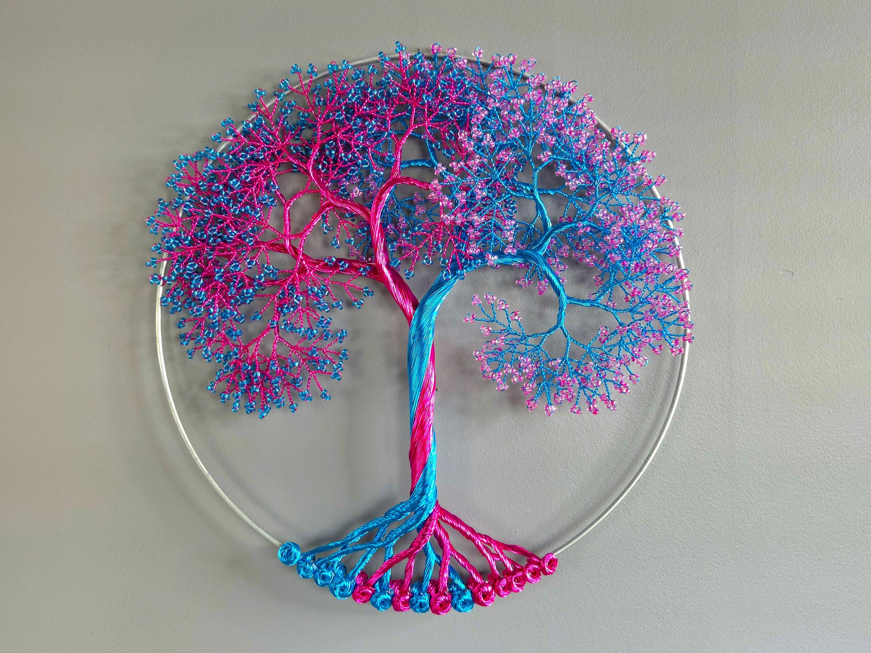 Decorative wall art of a tree with pink and blue branches on a plain background