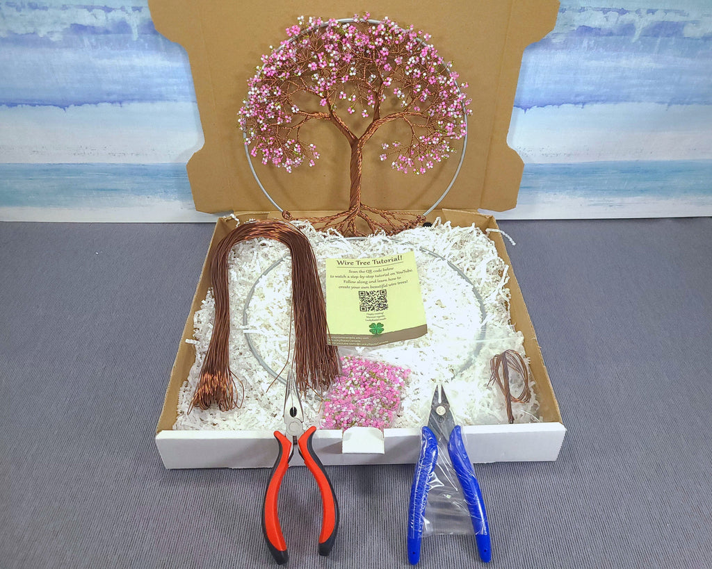 Craft kit with decorative tree, scissors, and pliers on a gray surface.