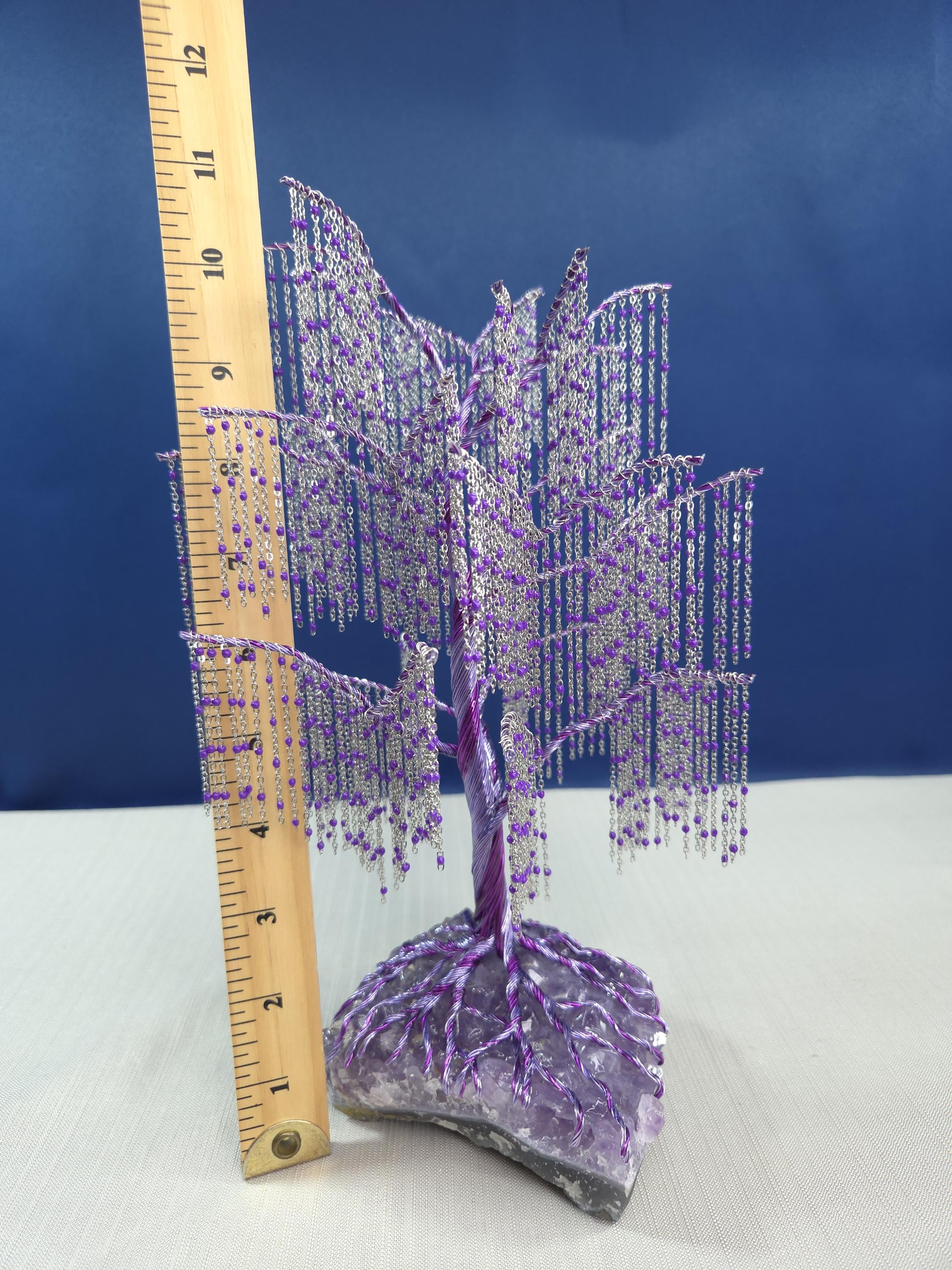 Decorative purple tree sculpture with a ruler for scale against a blue background