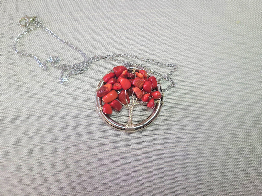 Necklace with a red bead tree of life pendant on a light gray background