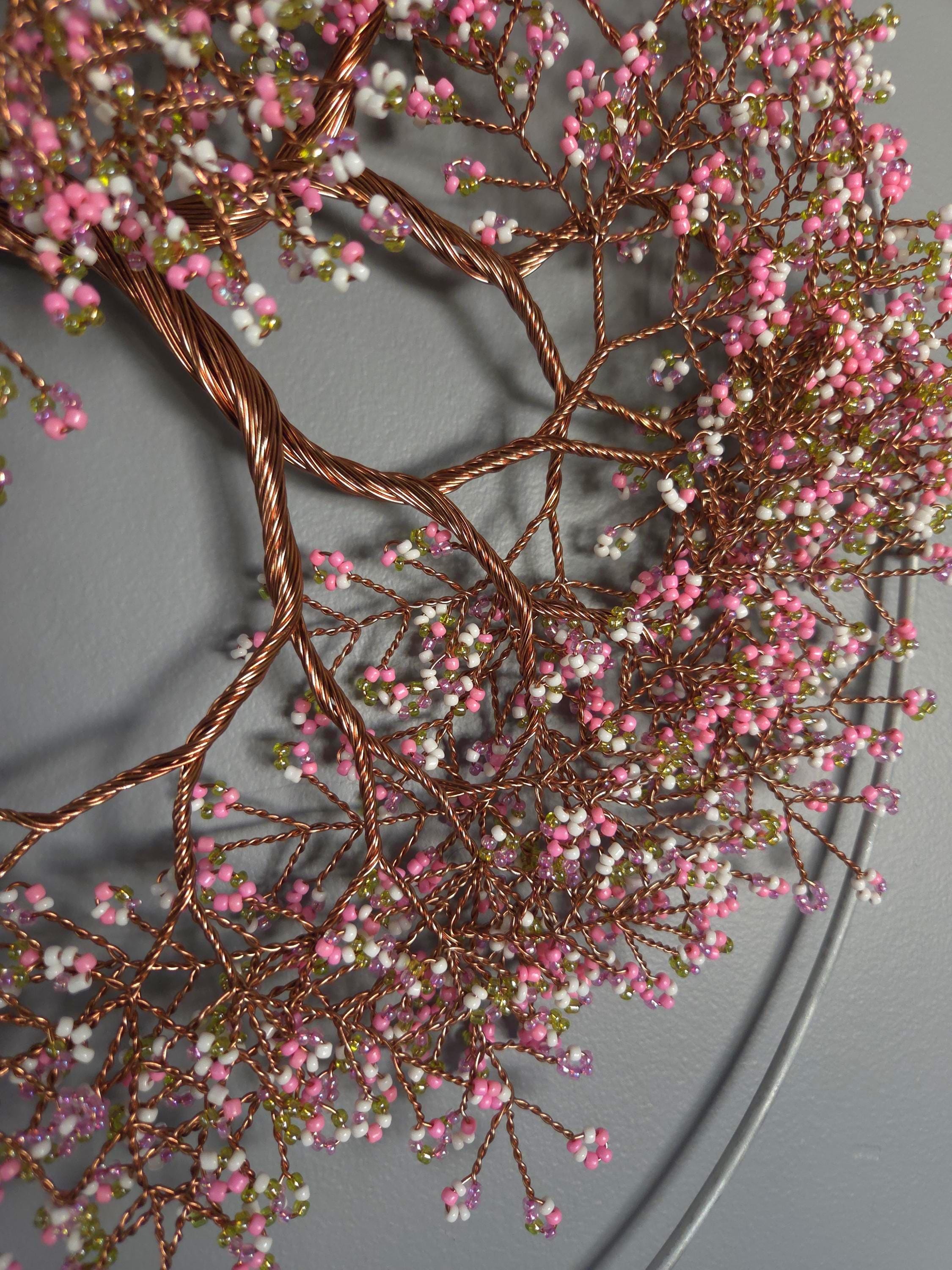 Decorative wall piece with pink and green beads on a gray background