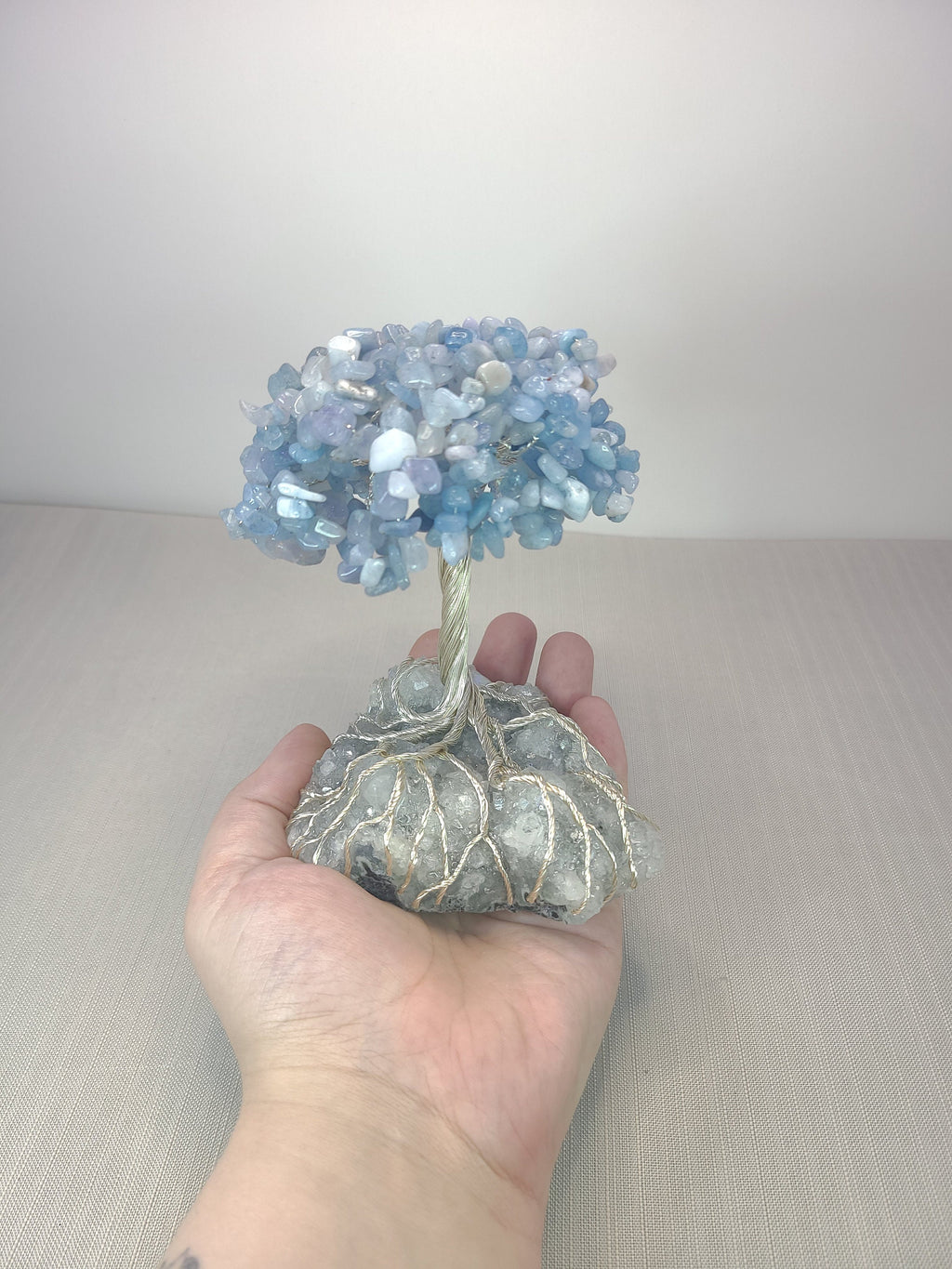 Hand holding a crystal tree with a plain background