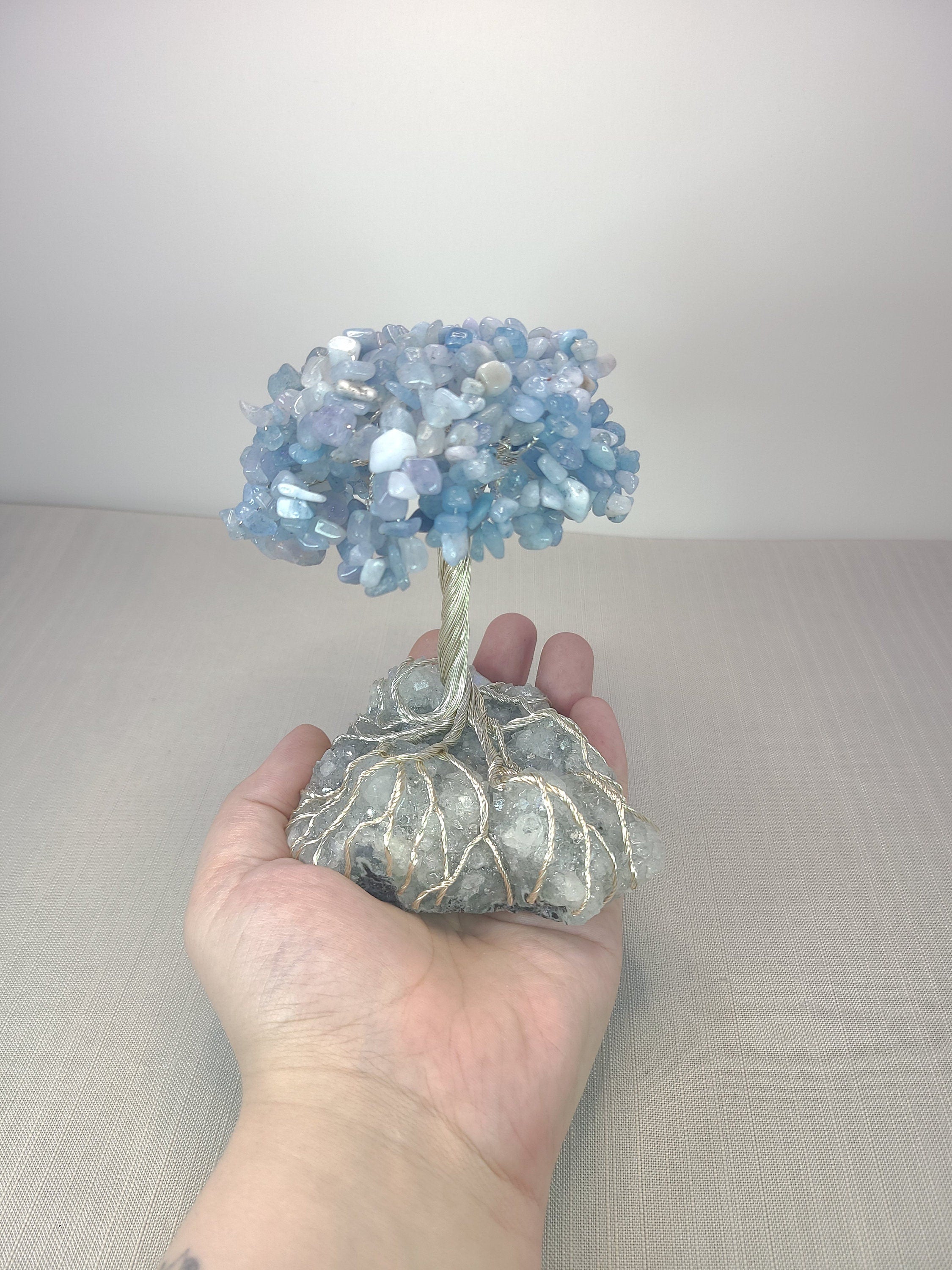 Hand holding a crystal tree with a plain background