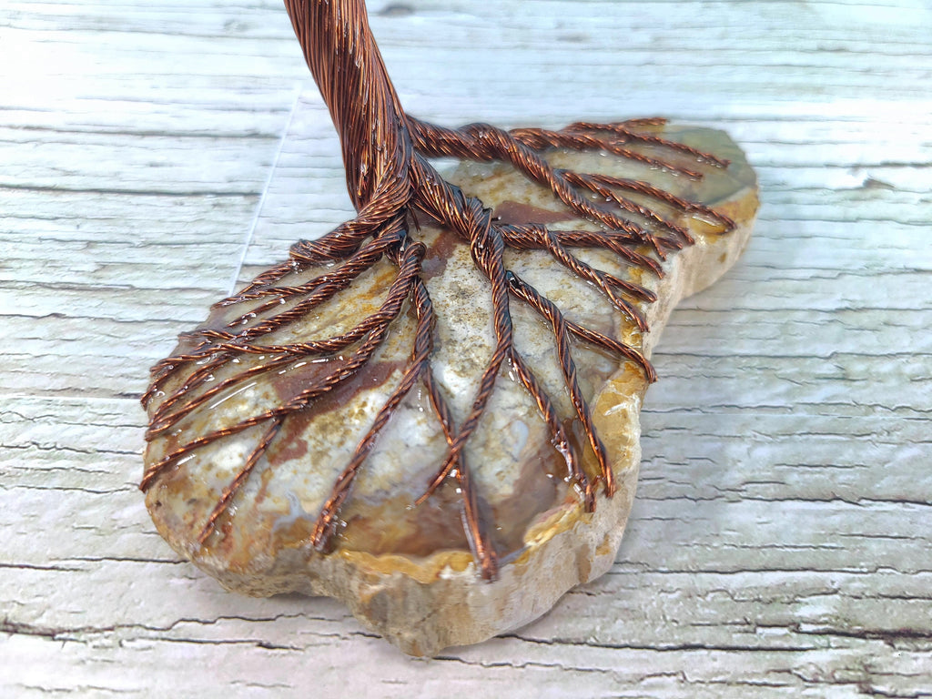 Decorative stone with copper wire art on a textured surface