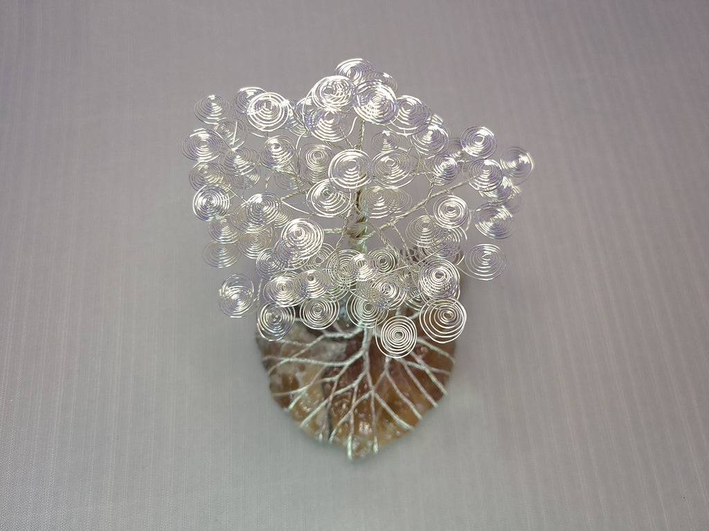 Decorative wall art with circular patterns on a leaf-shaped base against a gray background