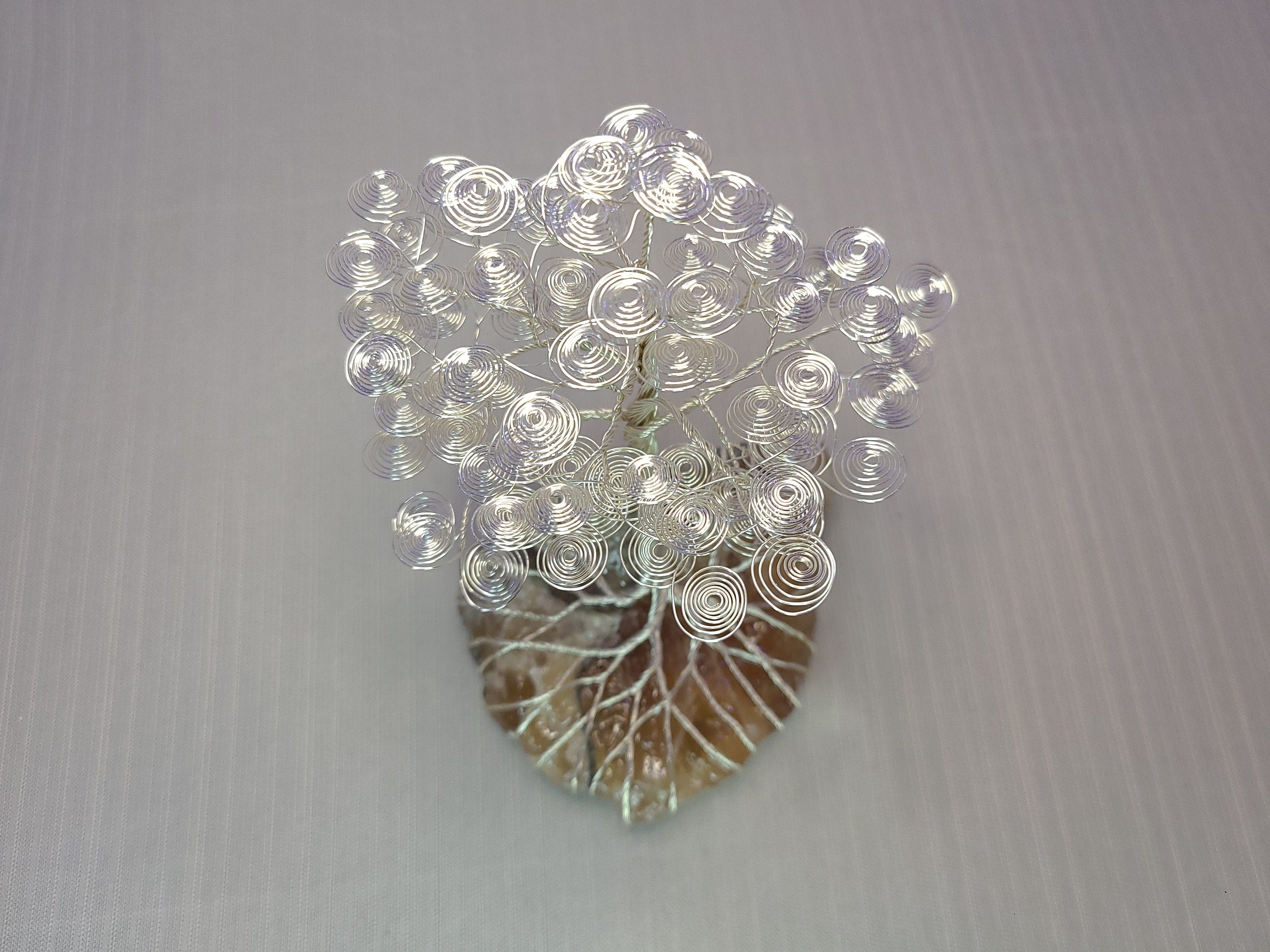 Decorative wall art with circular patterns on a leaf-shaped base against a gray background