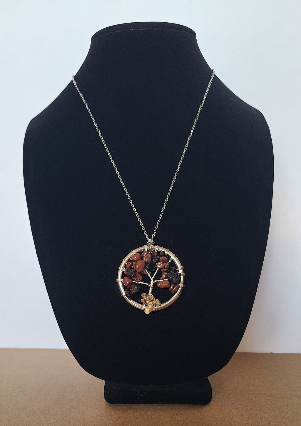 Necklace with a circular pendant on a black bust against a light blue background