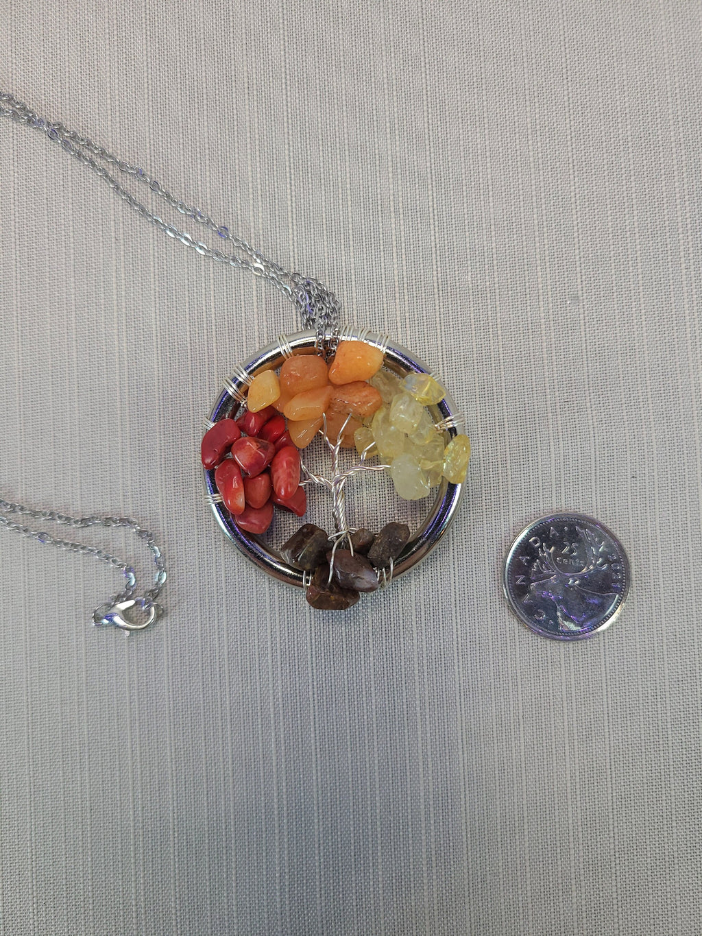 Necklace with a round pendant featuring colorful stones on a gray background