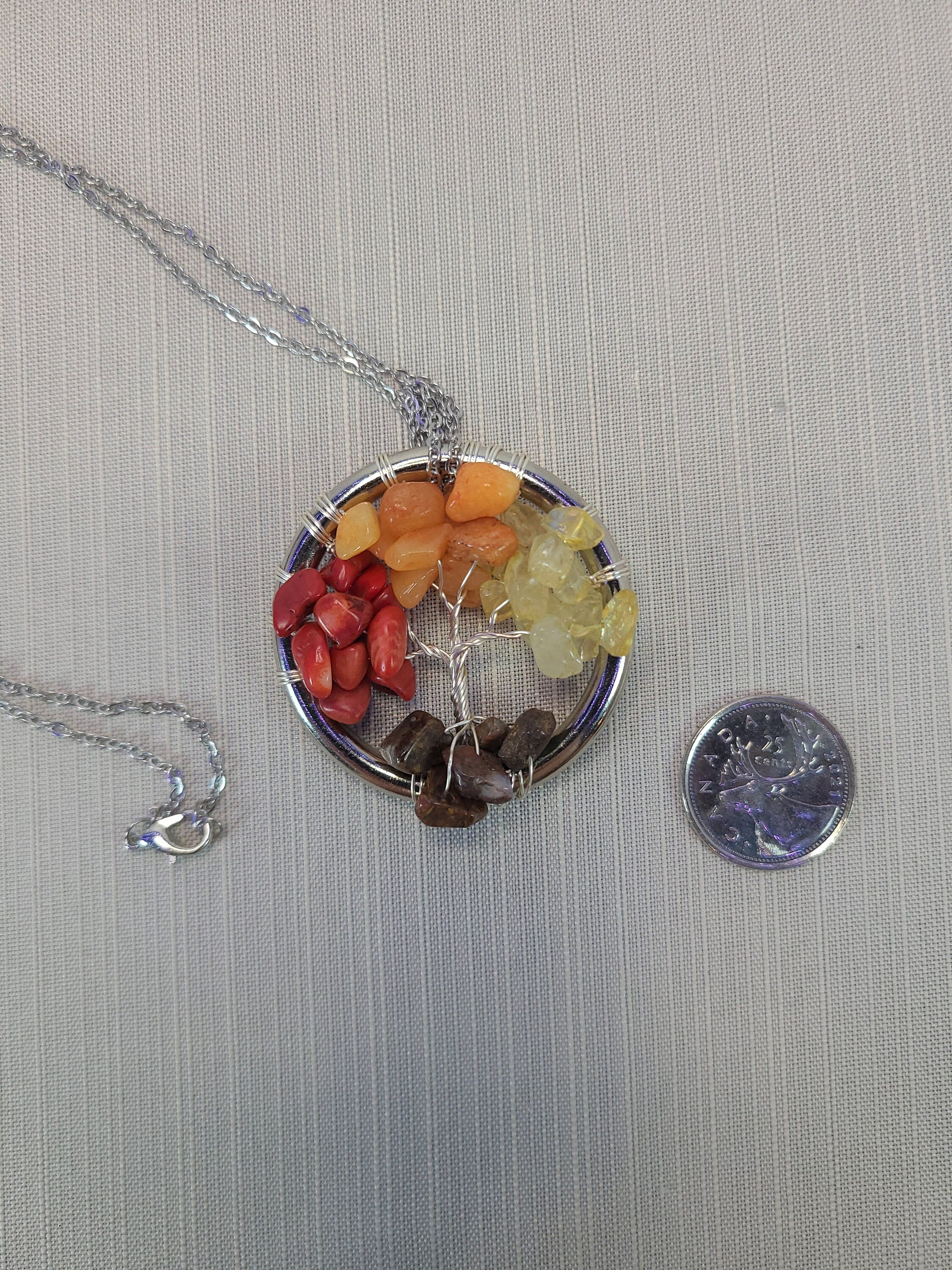 Necklace with a round pendant featuring colorful stones on a gray background