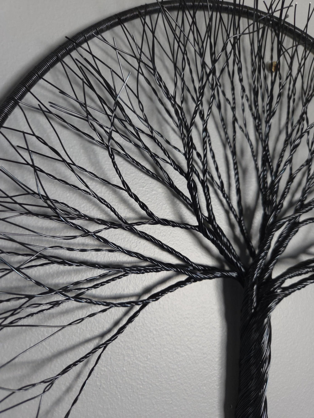 Black wire tree sculpture against a white wall