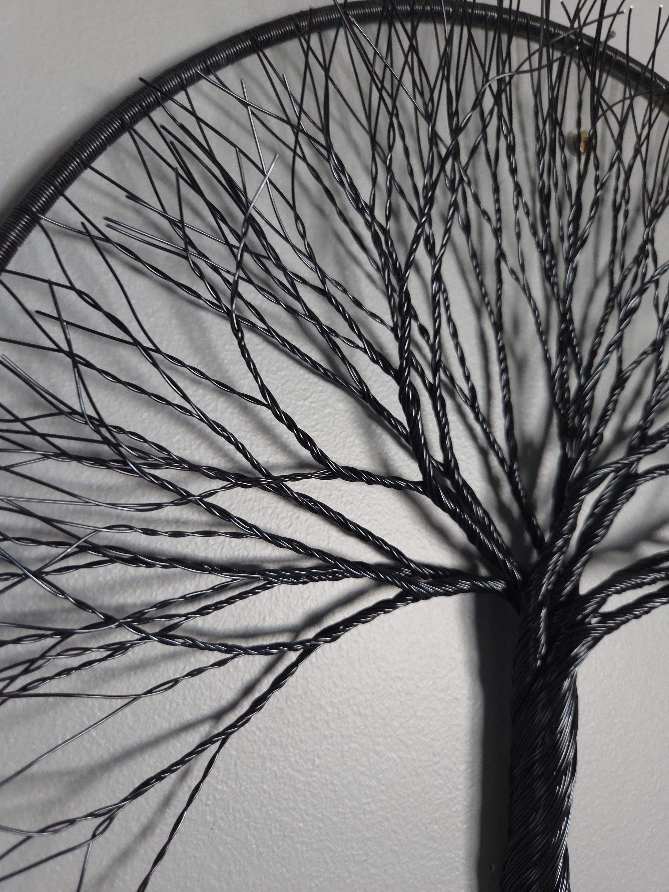 Black wire tree sculpture against a white wall