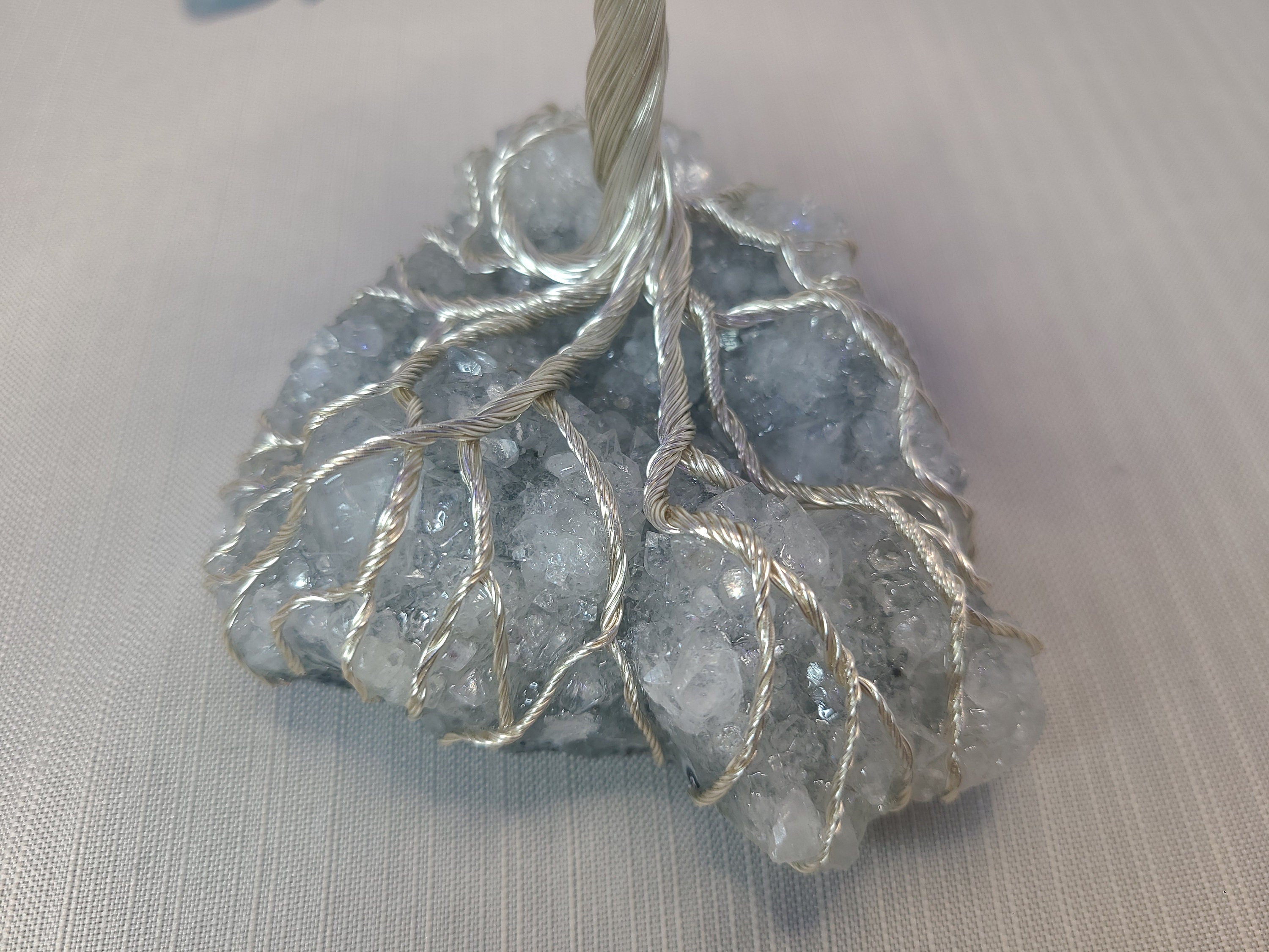 Decorative stone with silver wire wrapped around it on a light gray background