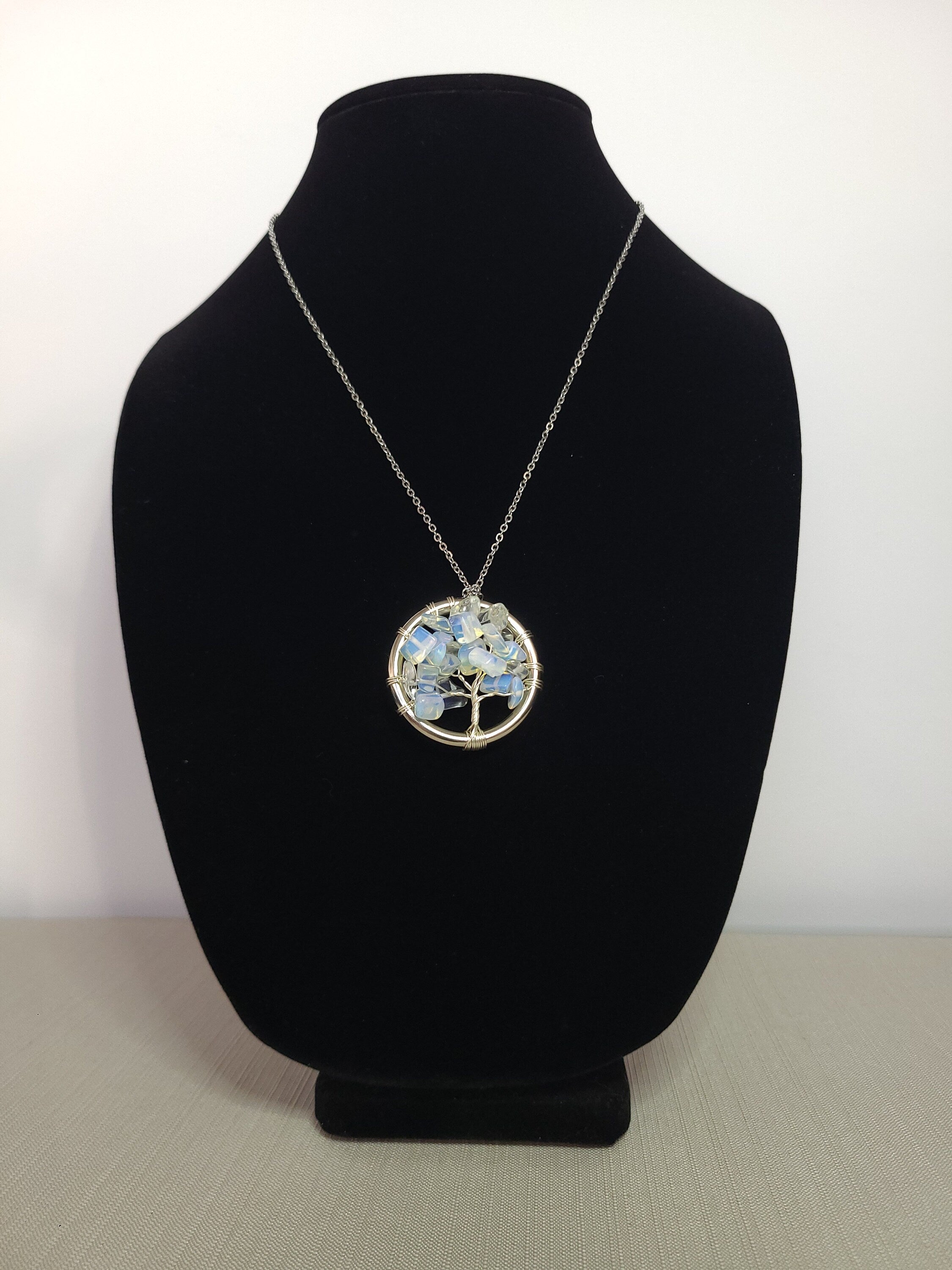 Necklace with a tree of life pendant on a black bust against a white background