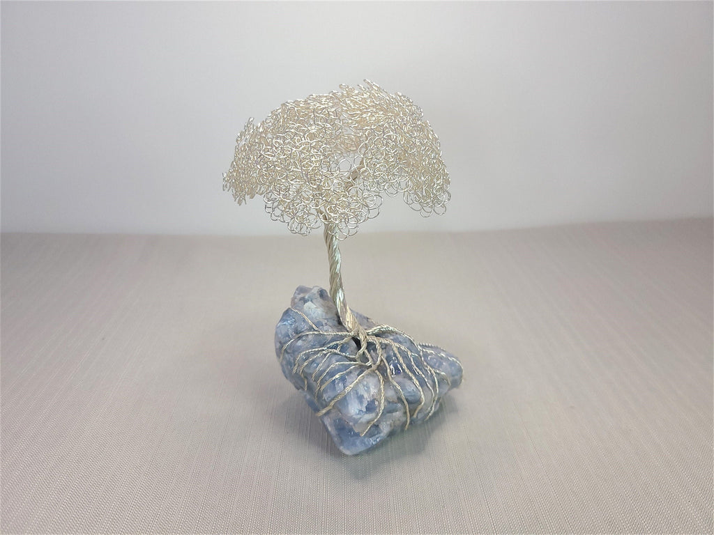 Decorative stone with a wire tree sculpture on a neutral background