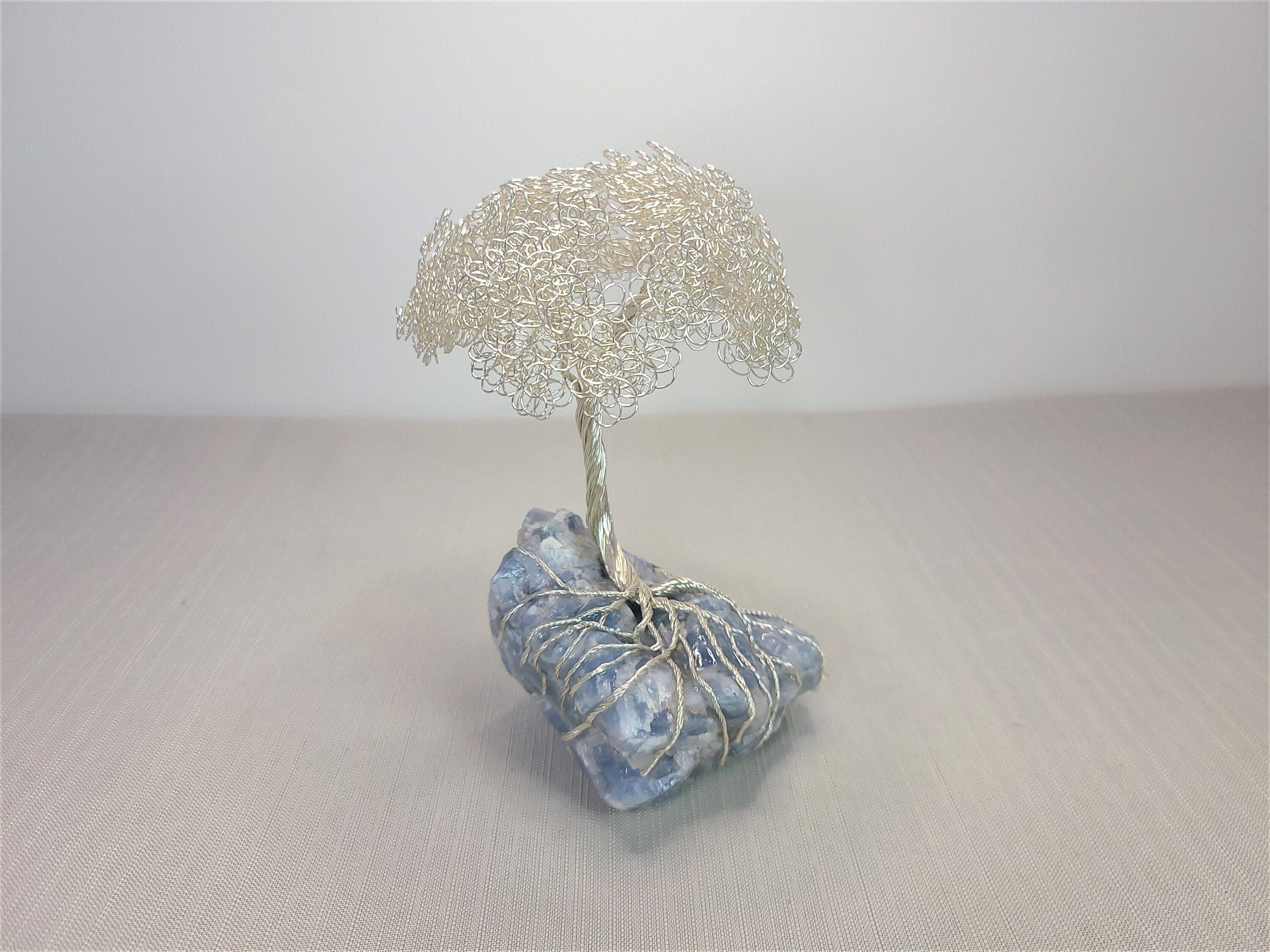 Decorative stone with a wire tree sculpture on a neutral background