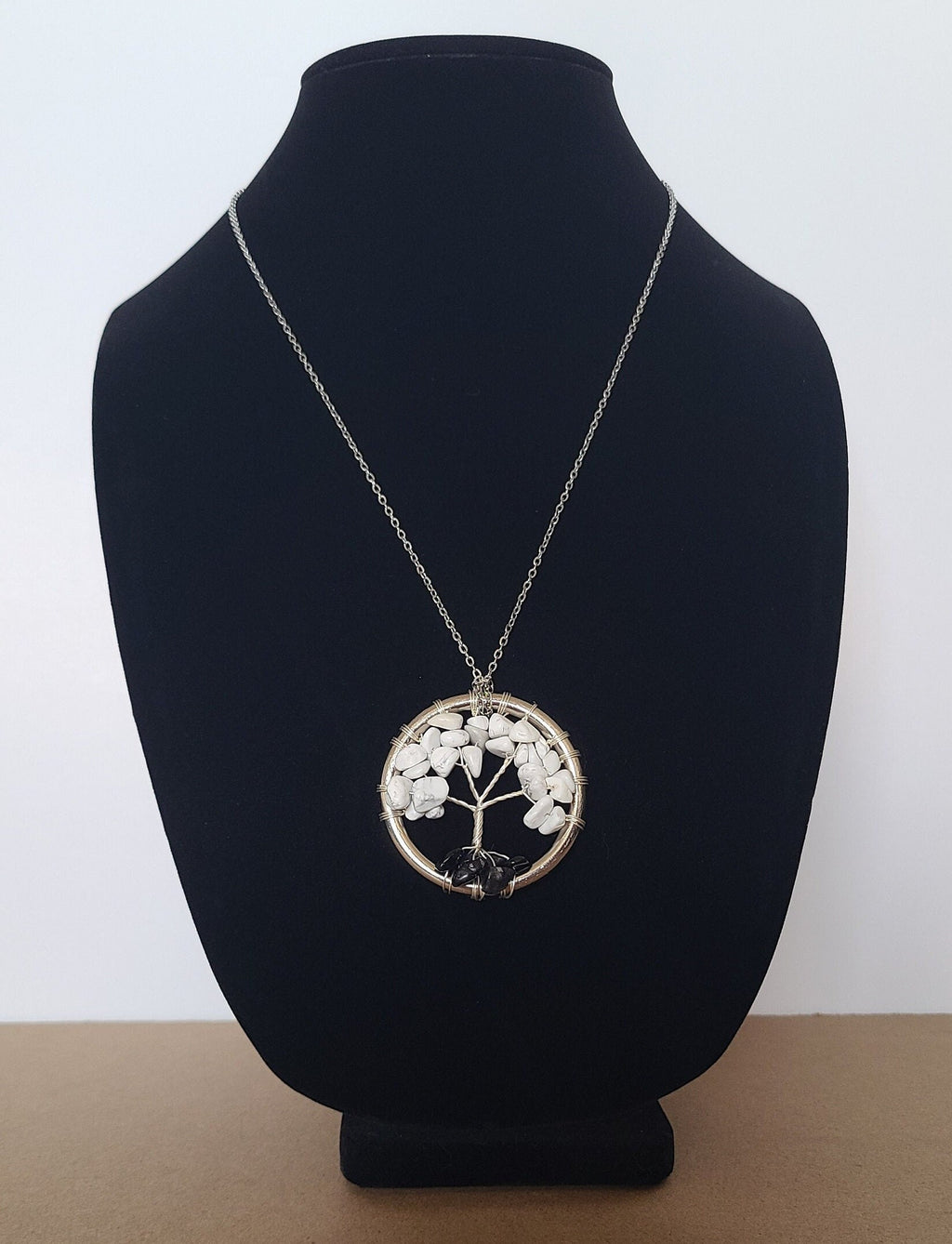 Necklace with a tree pendant on a black bust against a white background