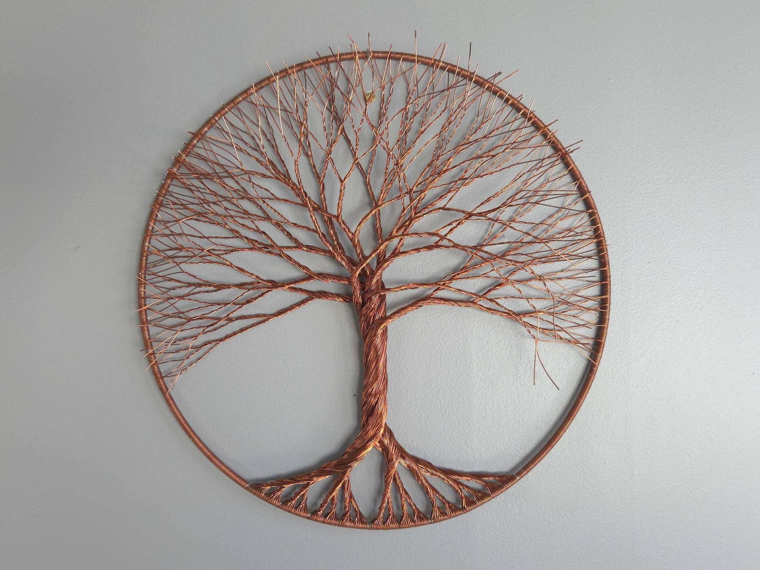 Decorative wall art of a tree with a circular frame on a plain background