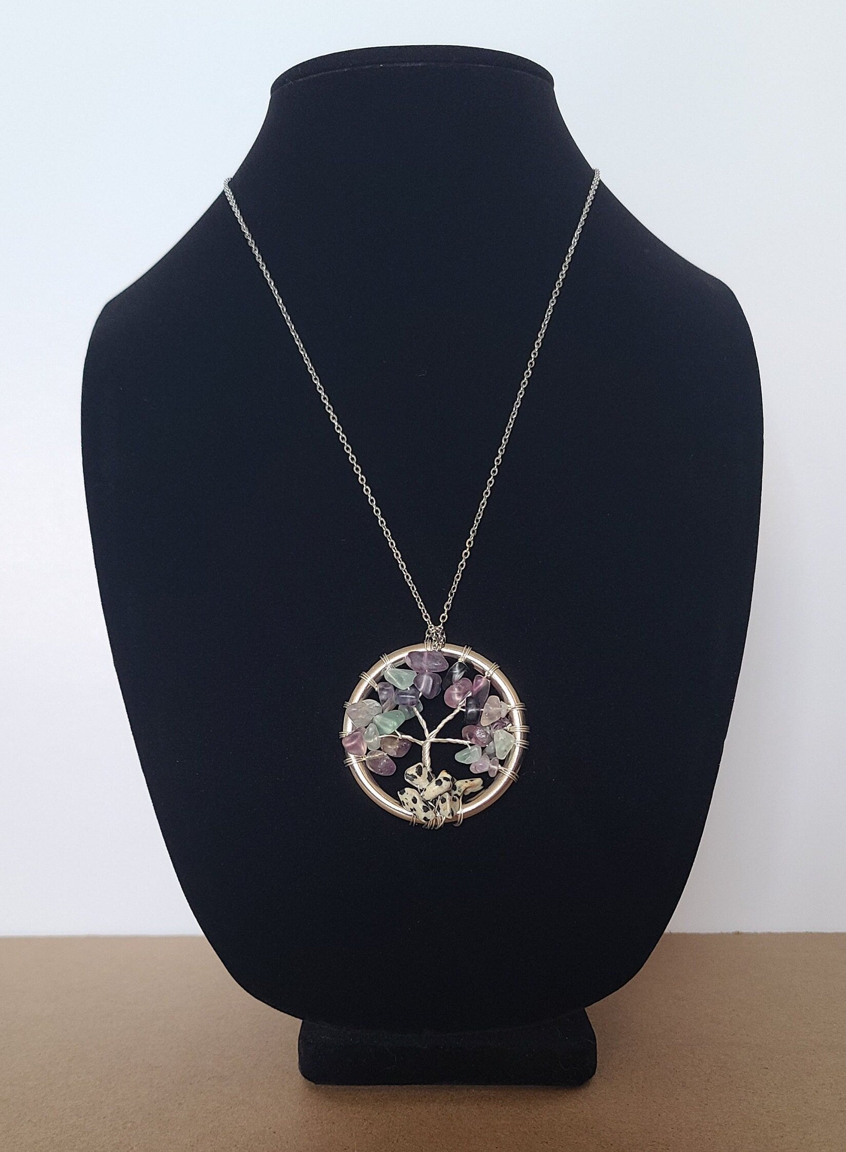 Necklace with a tree of life pendant on a black bust against a white background