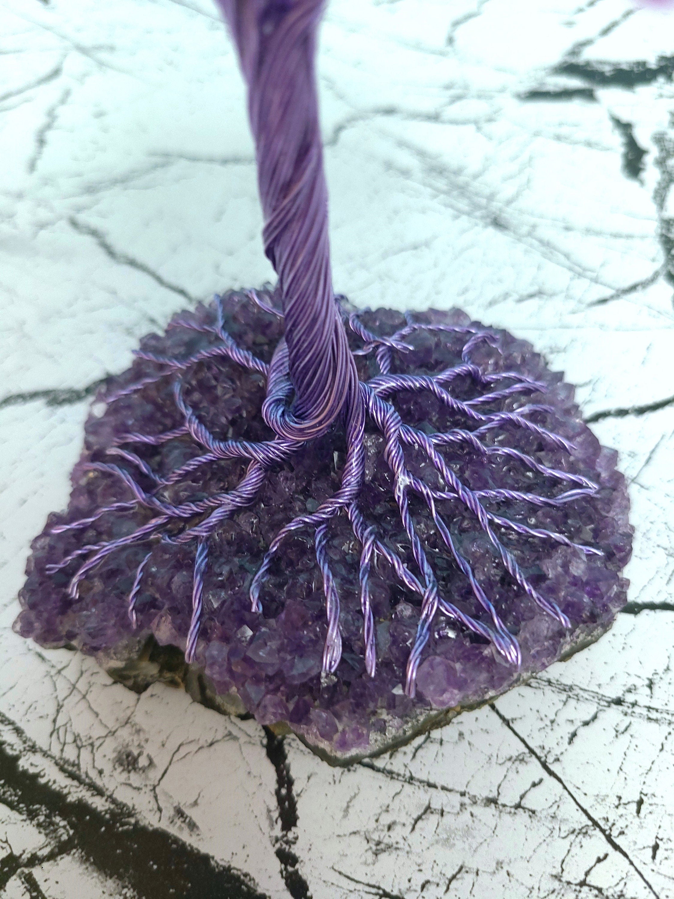 Purple yarn tied to a textured purple stone on a white background