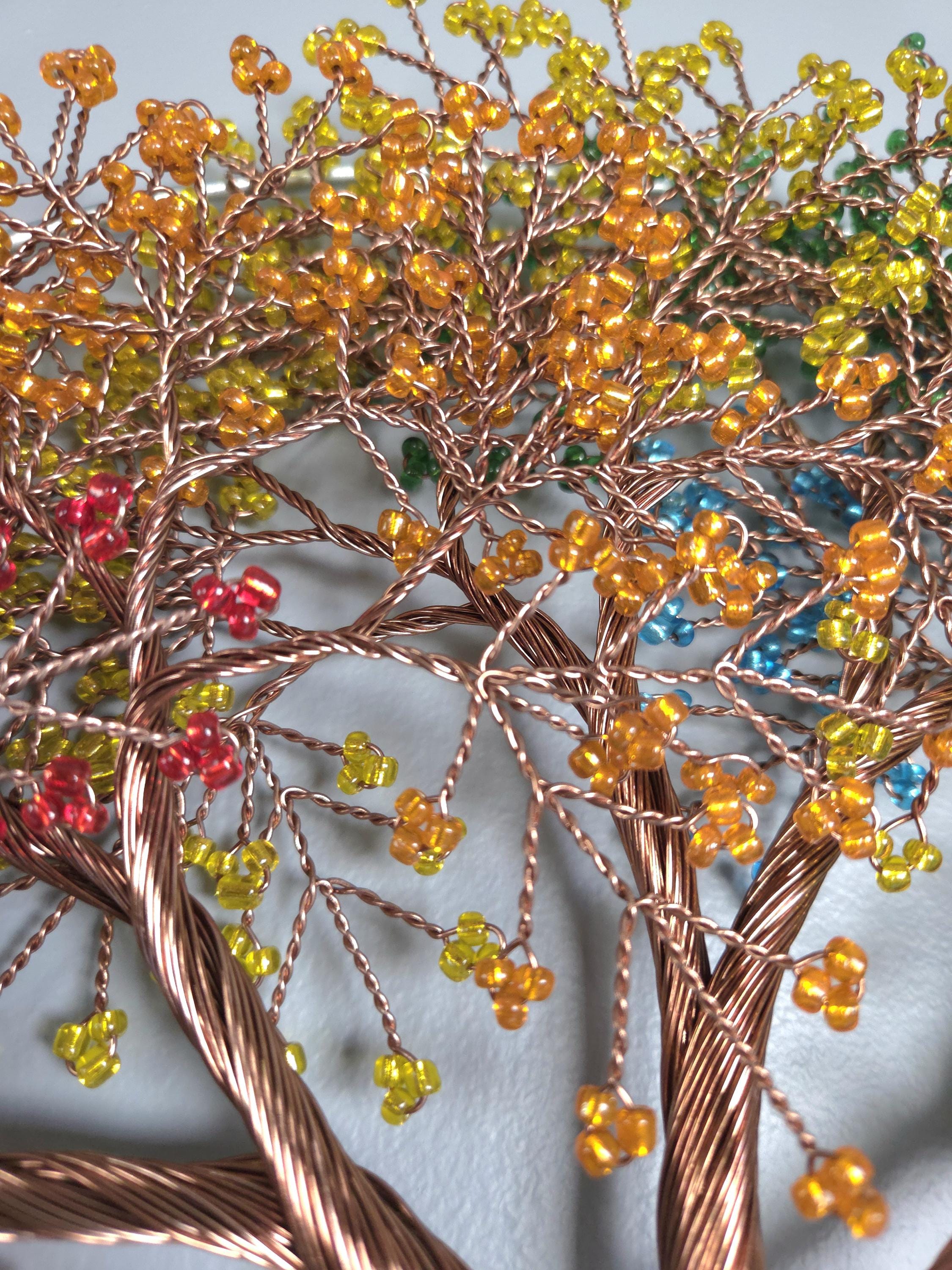 Decorative tree made of copper wire with colorful beads on a light gray background