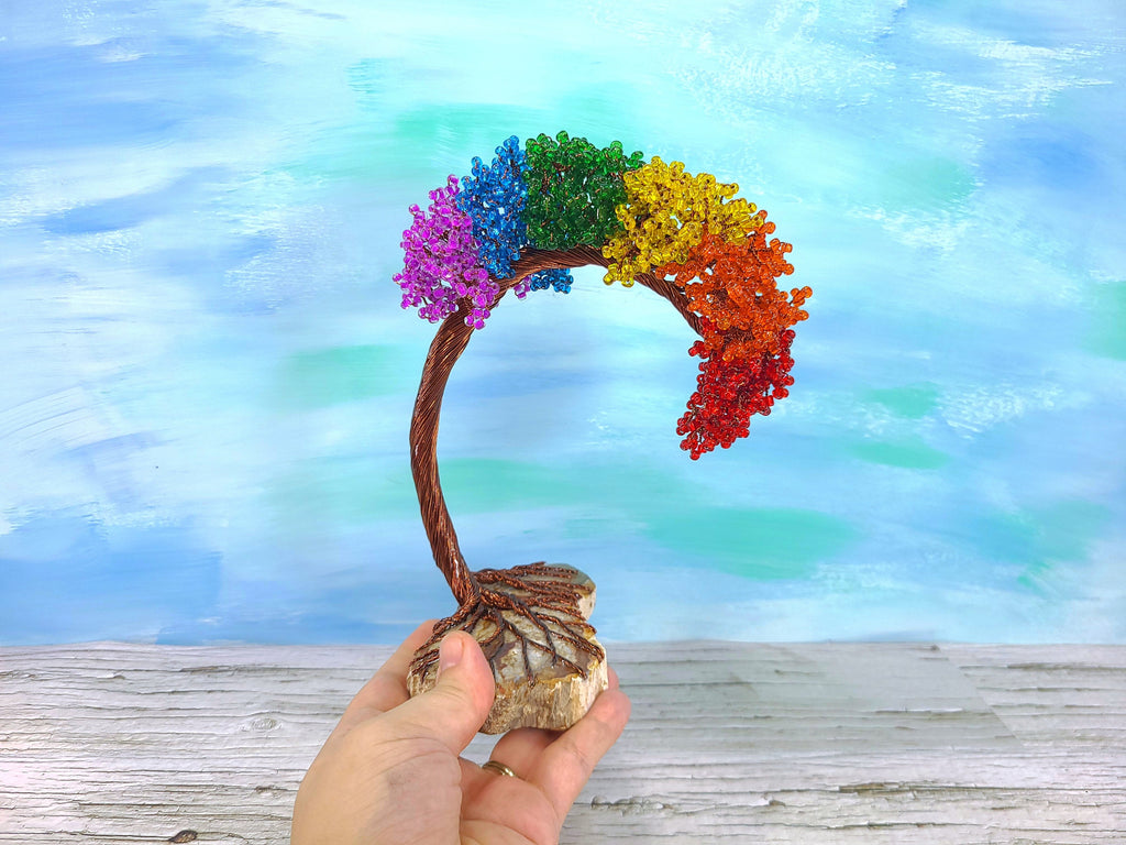 Colorful tree-shaped object held by a hand with a blurred natural background
